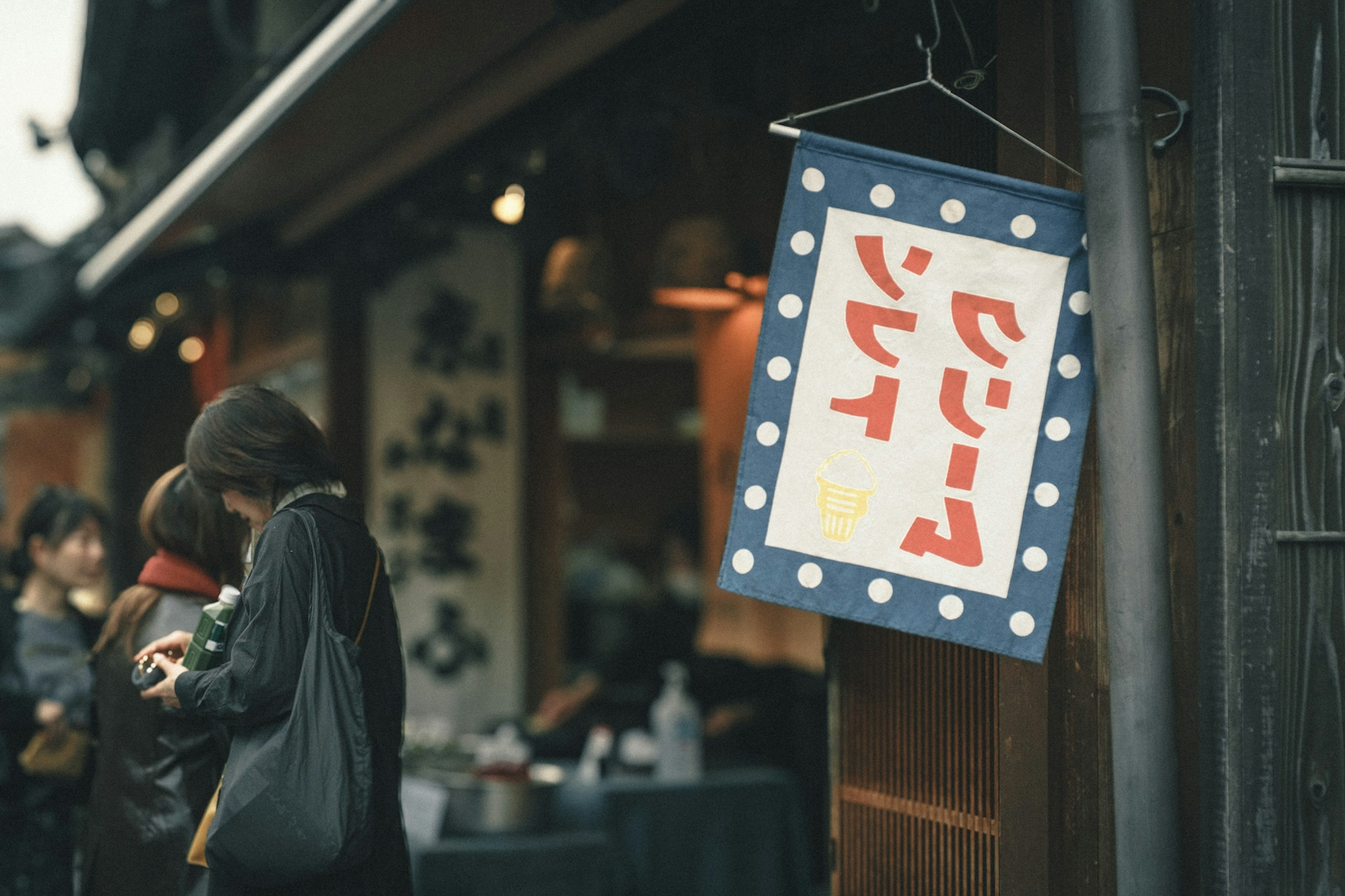 日本傳統商業街的場景，招牌上用白色字母寫著冰淇淋