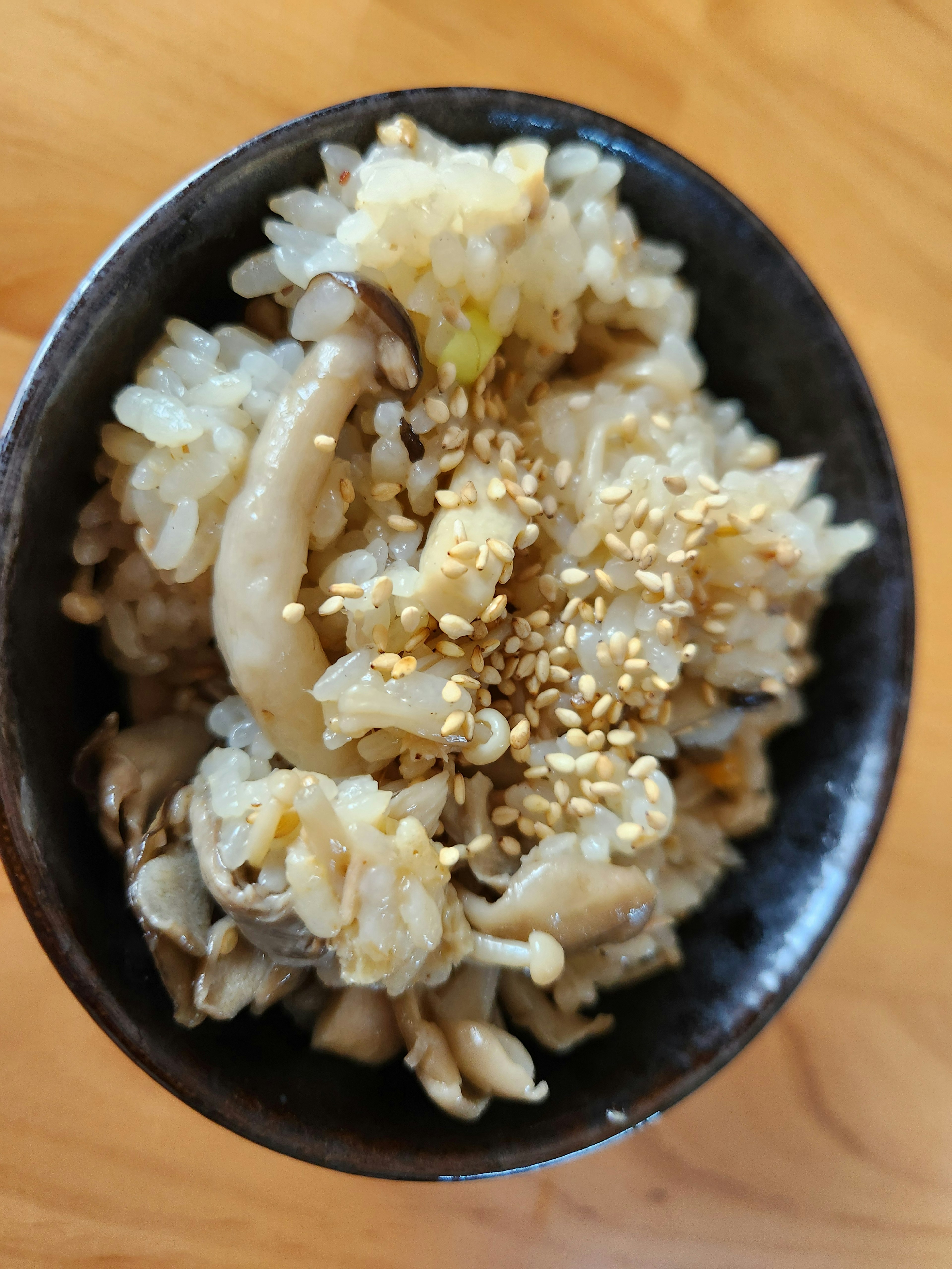 A bowl of savory rice with mushrooms topped with sesame seeds