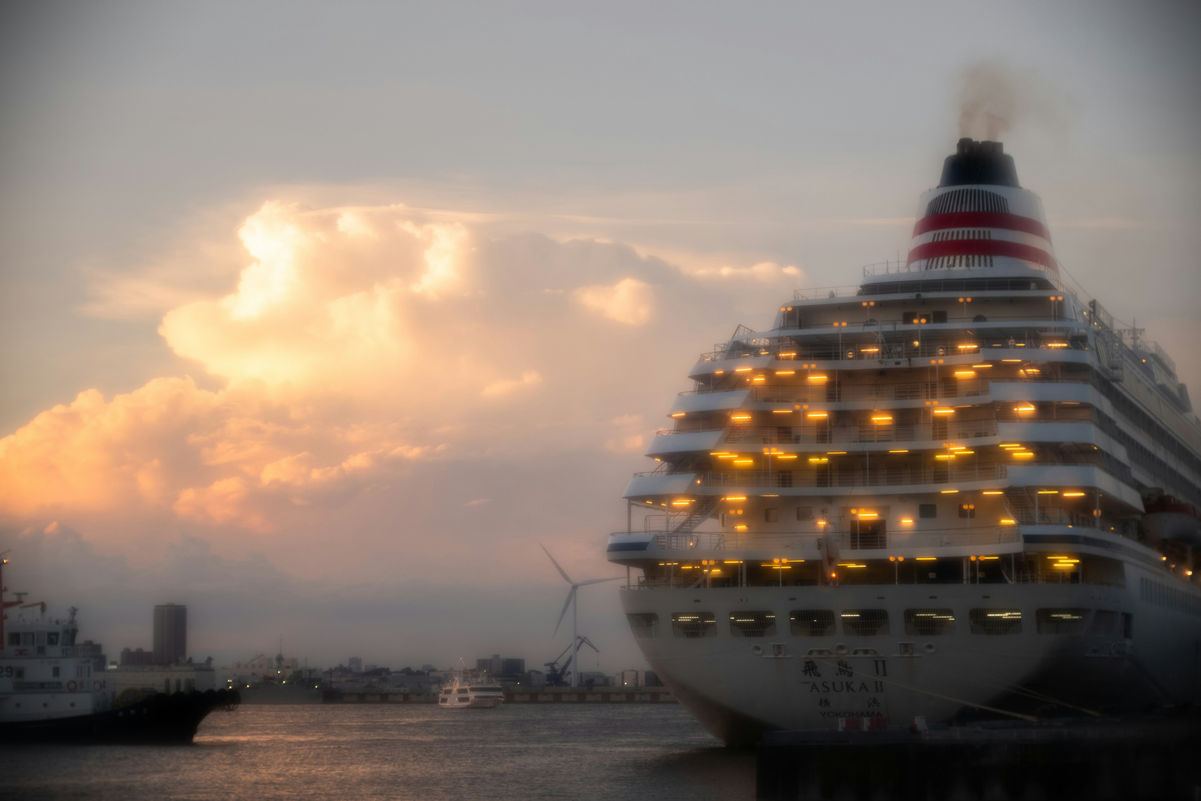 Barco de crucero de lujo iluminado al atardecer con nubes dramáticas