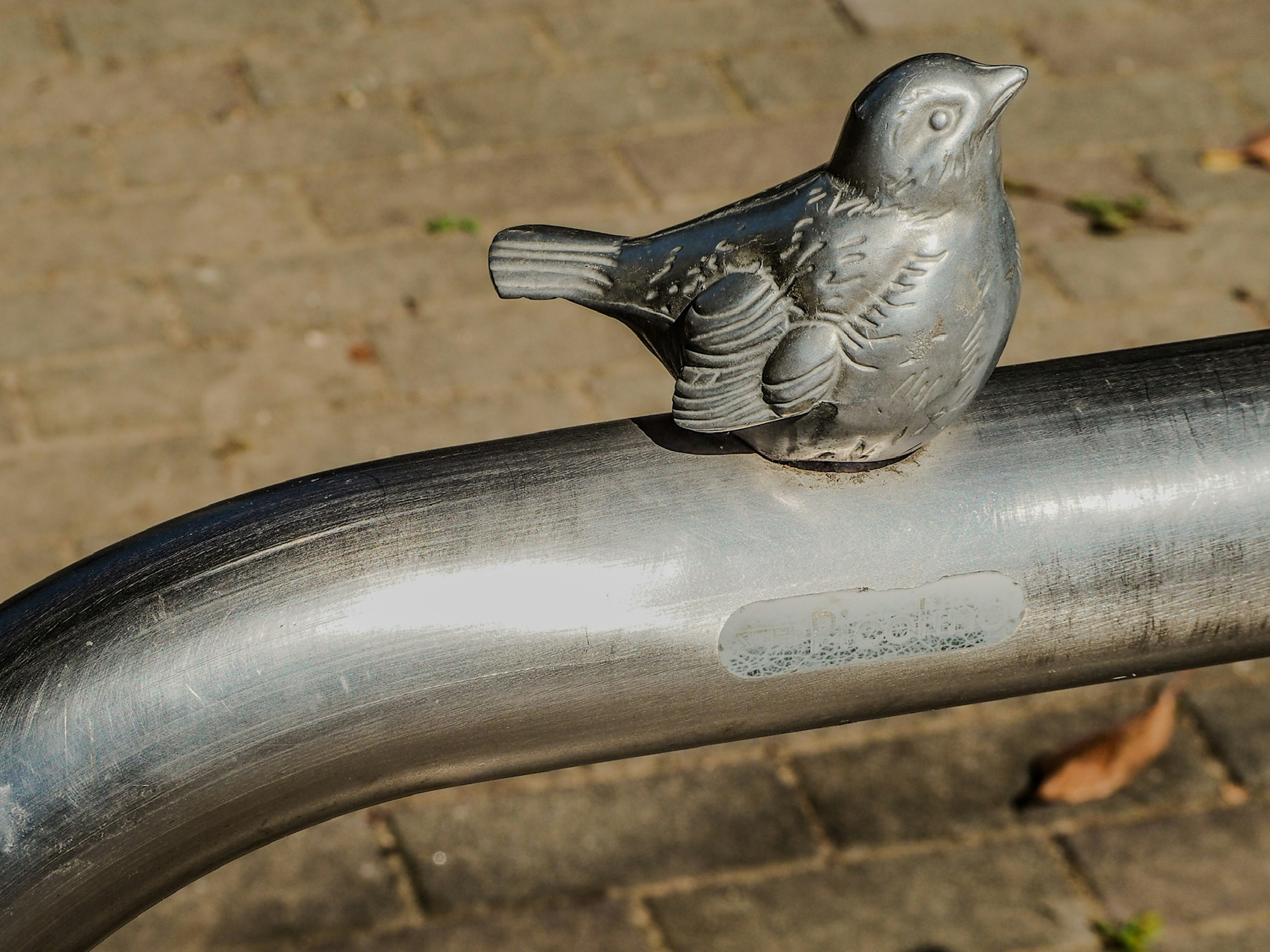 Una escultura de pájaro de metal posada sobre un tubo