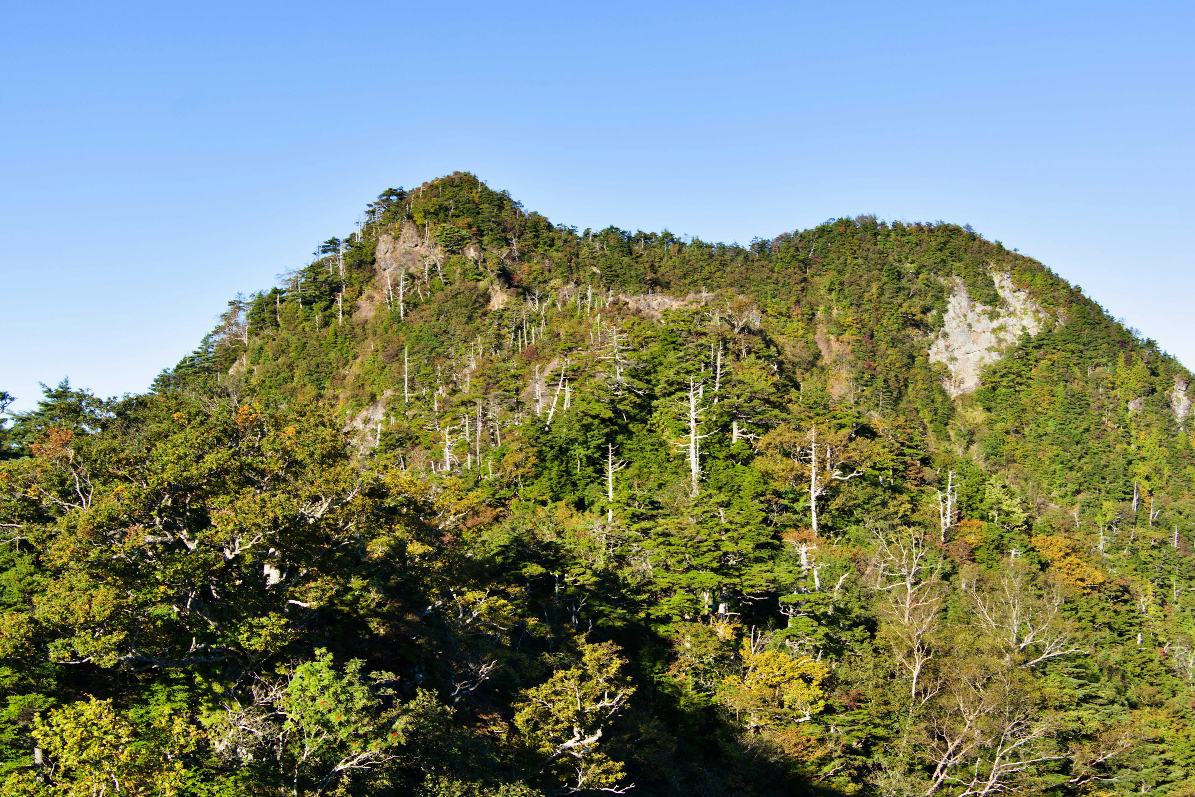 Paisaje montañoso verde bajo un cielo azul claro