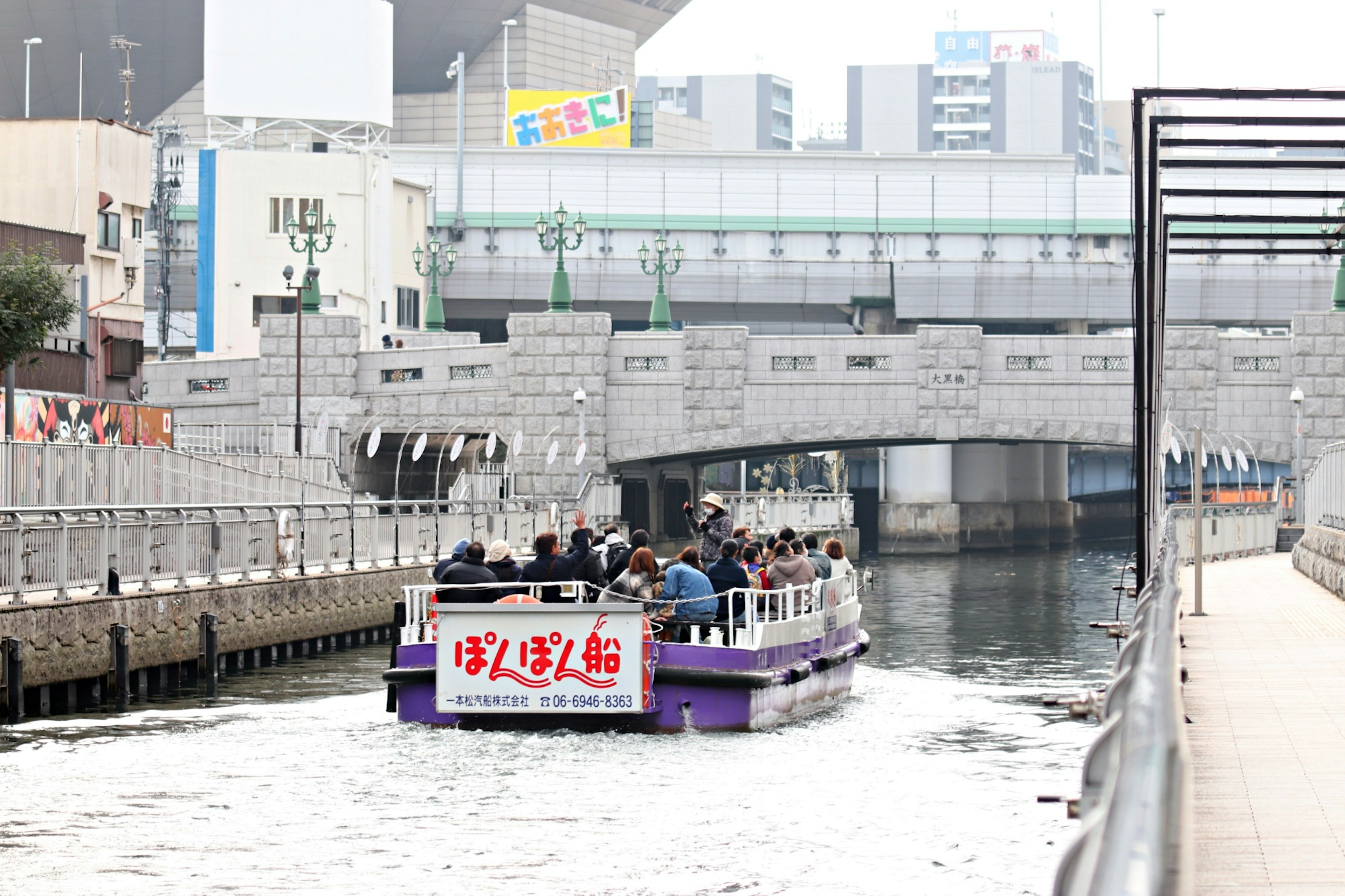 Touristenboot fährt auf einem Fluss mit einer Steinbrücke im Hintergrund