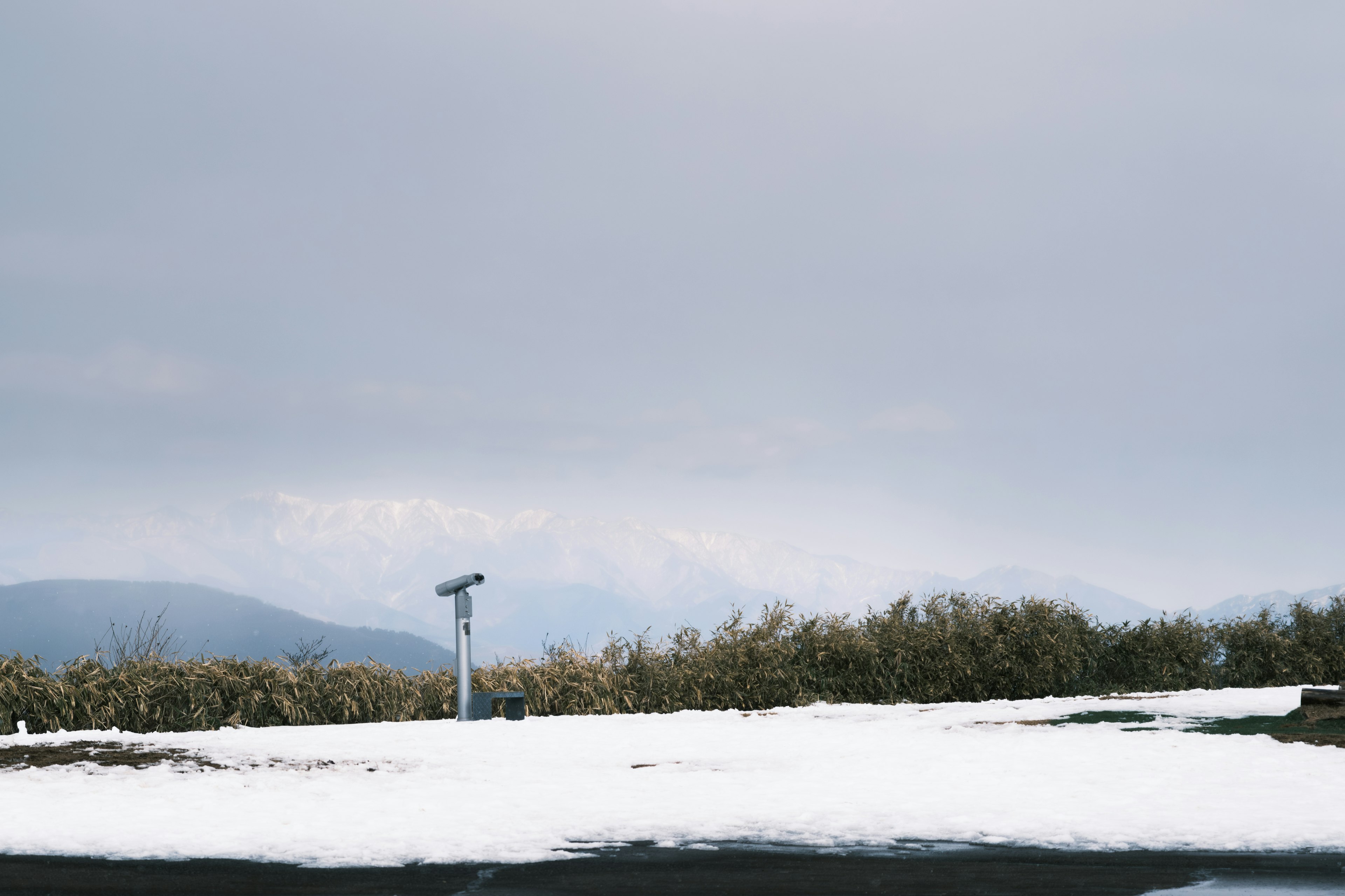 Schneebedeckte Landschaft mit fernen Bergen unter bewölktem Himmel