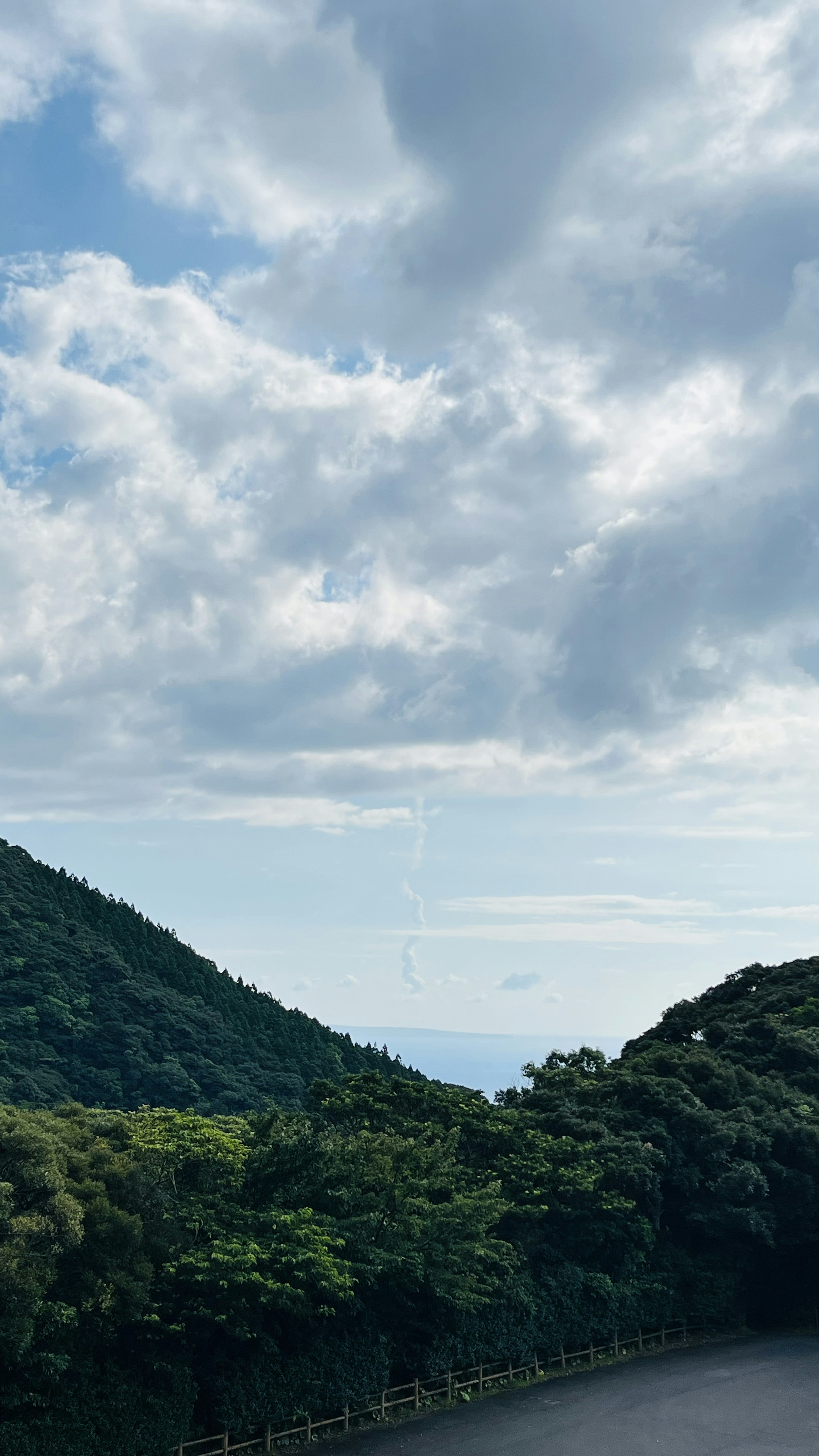 青い空と白い雲に囲まれた緑の山々の風景