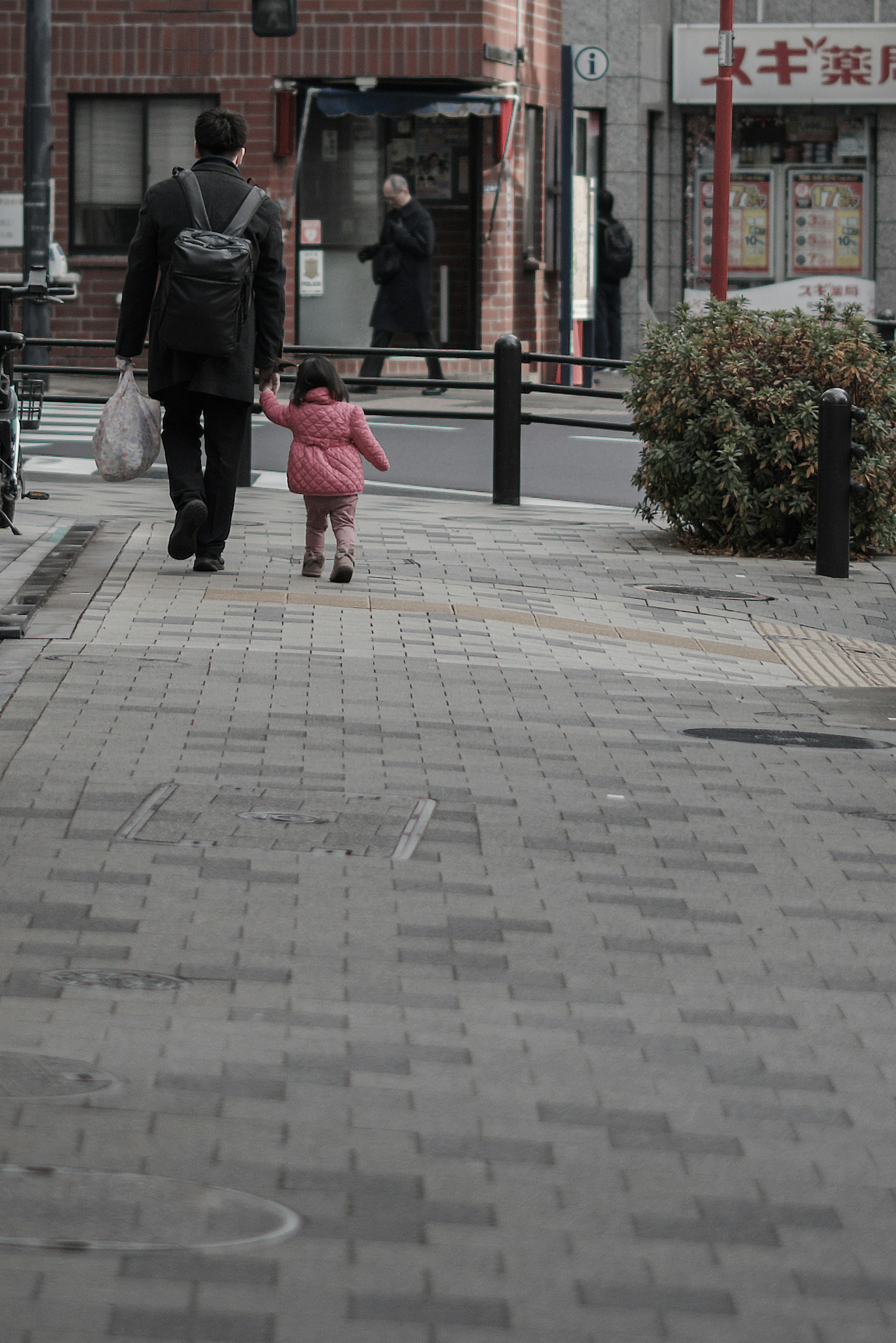 Hombre caminando por la calle con un niño en abrigo rosa