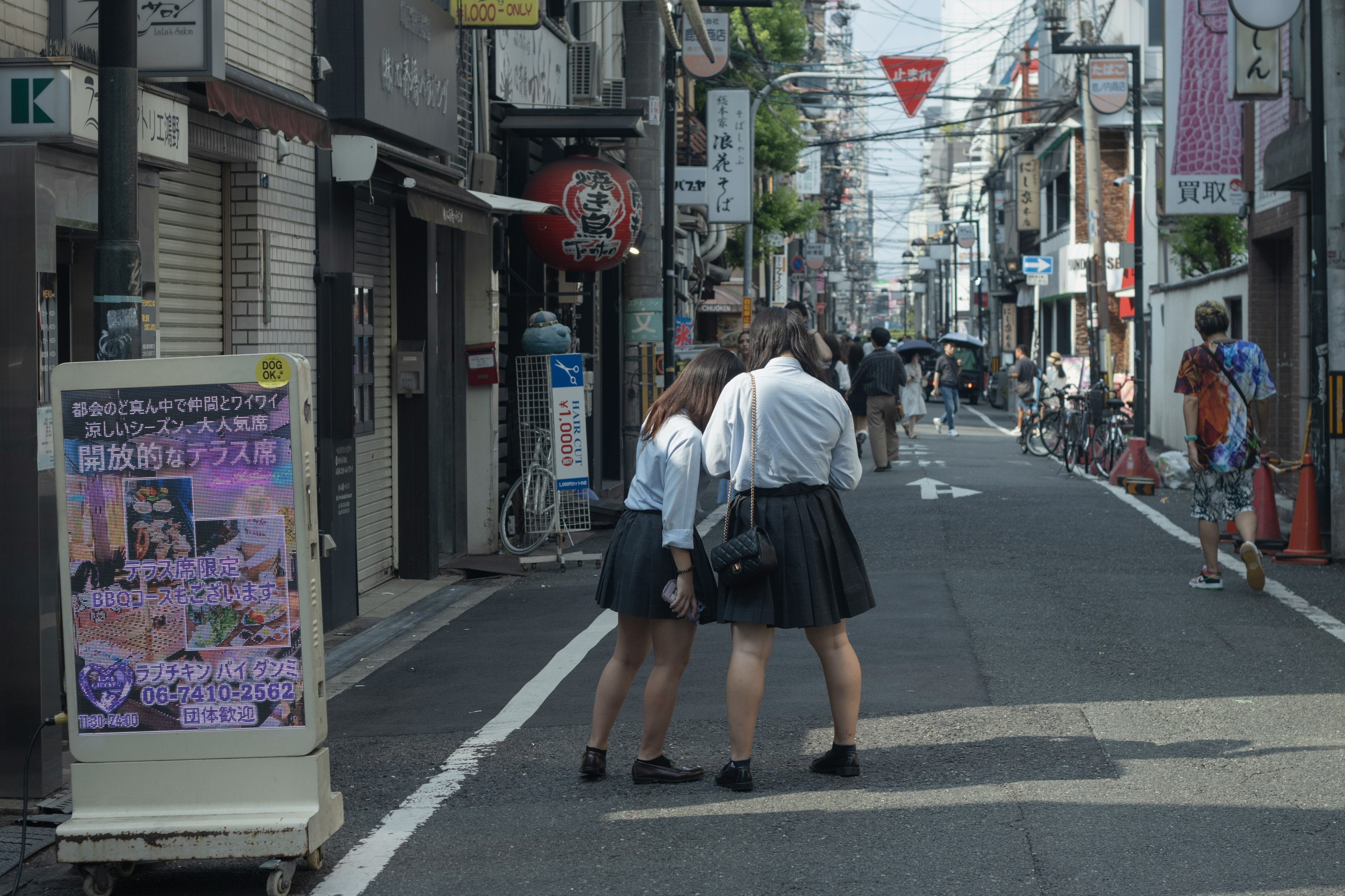 東京の街並みを背景に二人の学生が歩いている