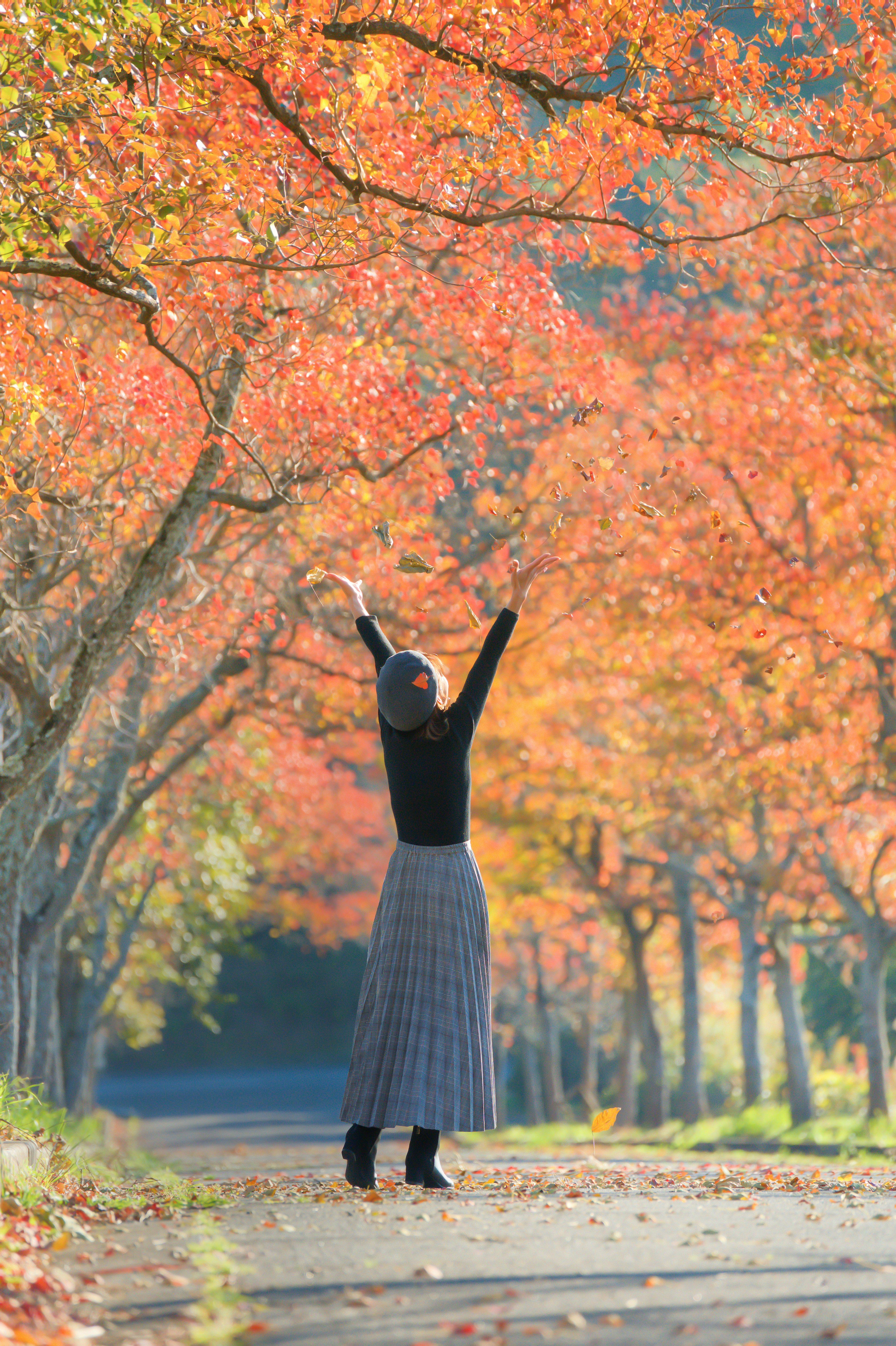 秋の紅葉を背景に両手を上げて喜ぶ女性