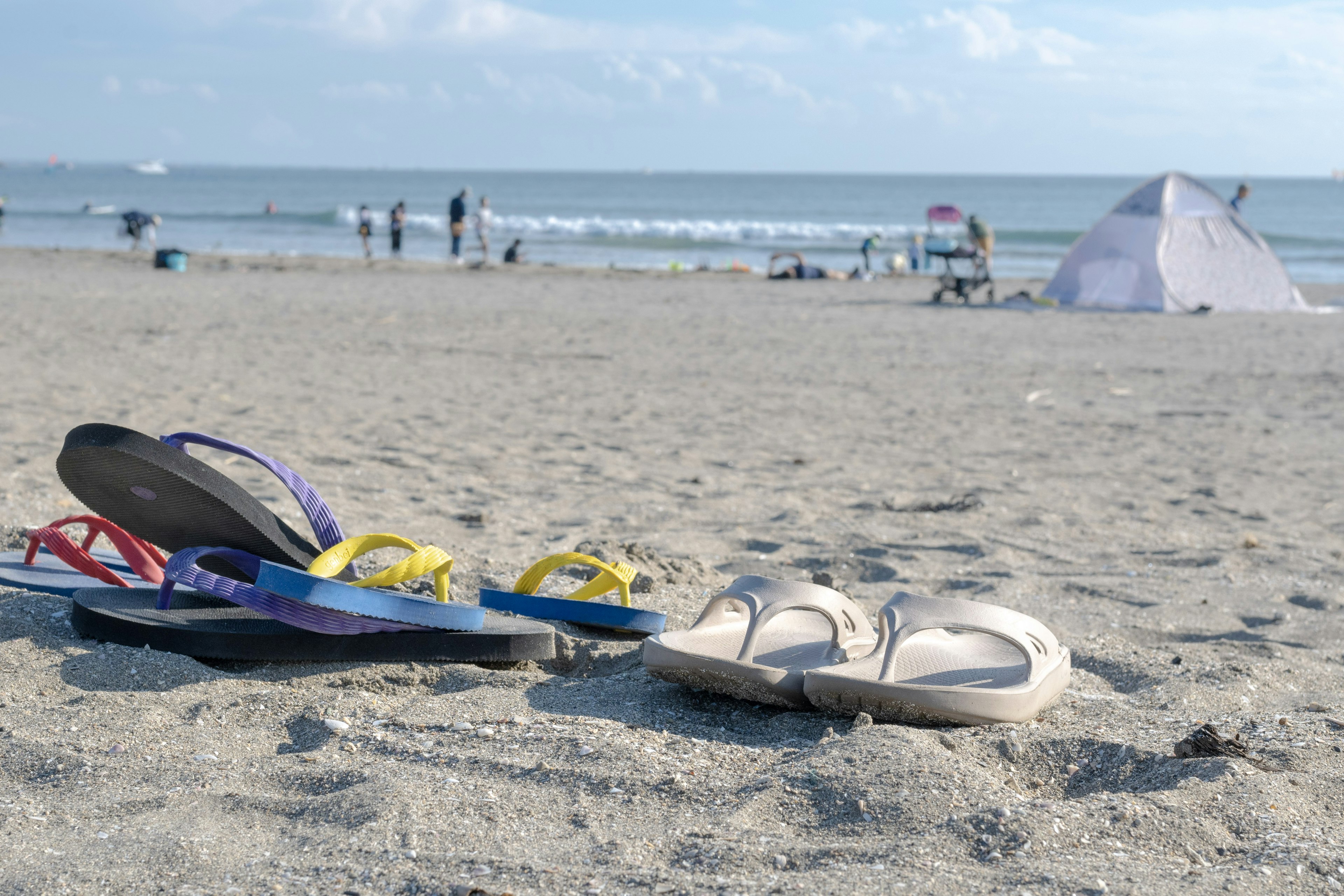 Chanclas en la playa de arena con vista al océano