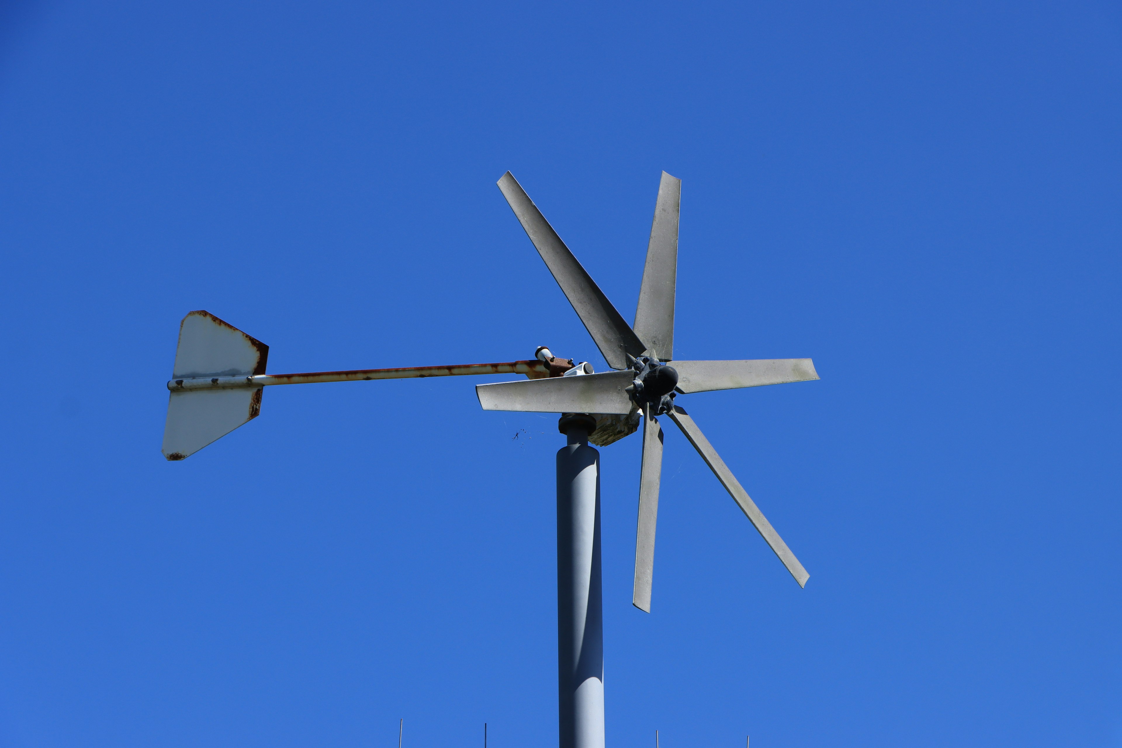 Aspas y mástil de un aerogenerador contra un cielo azul claro