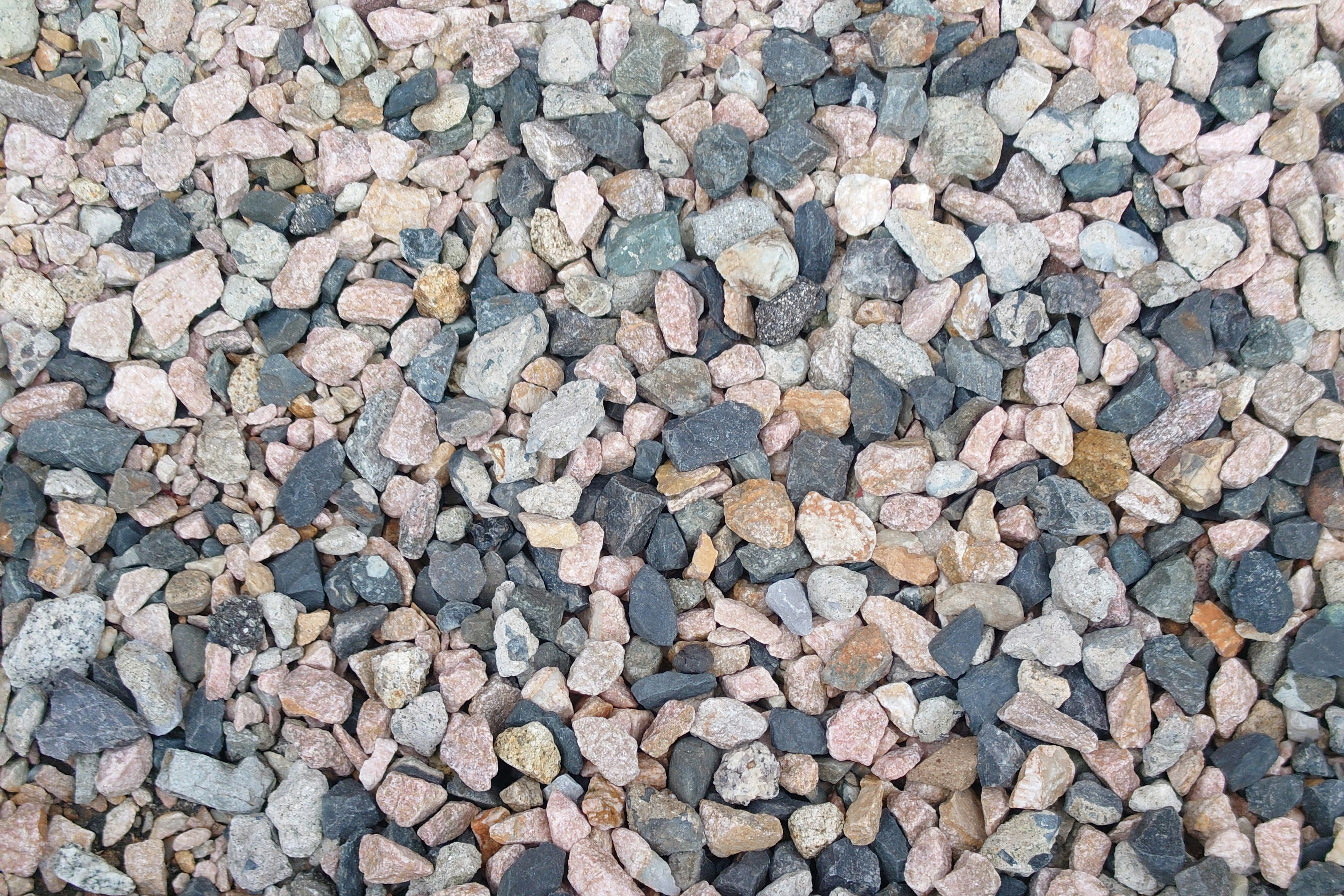 Una vista cercana de una superficie cubierta de pequeñas piedras en tonos de gris y rosa