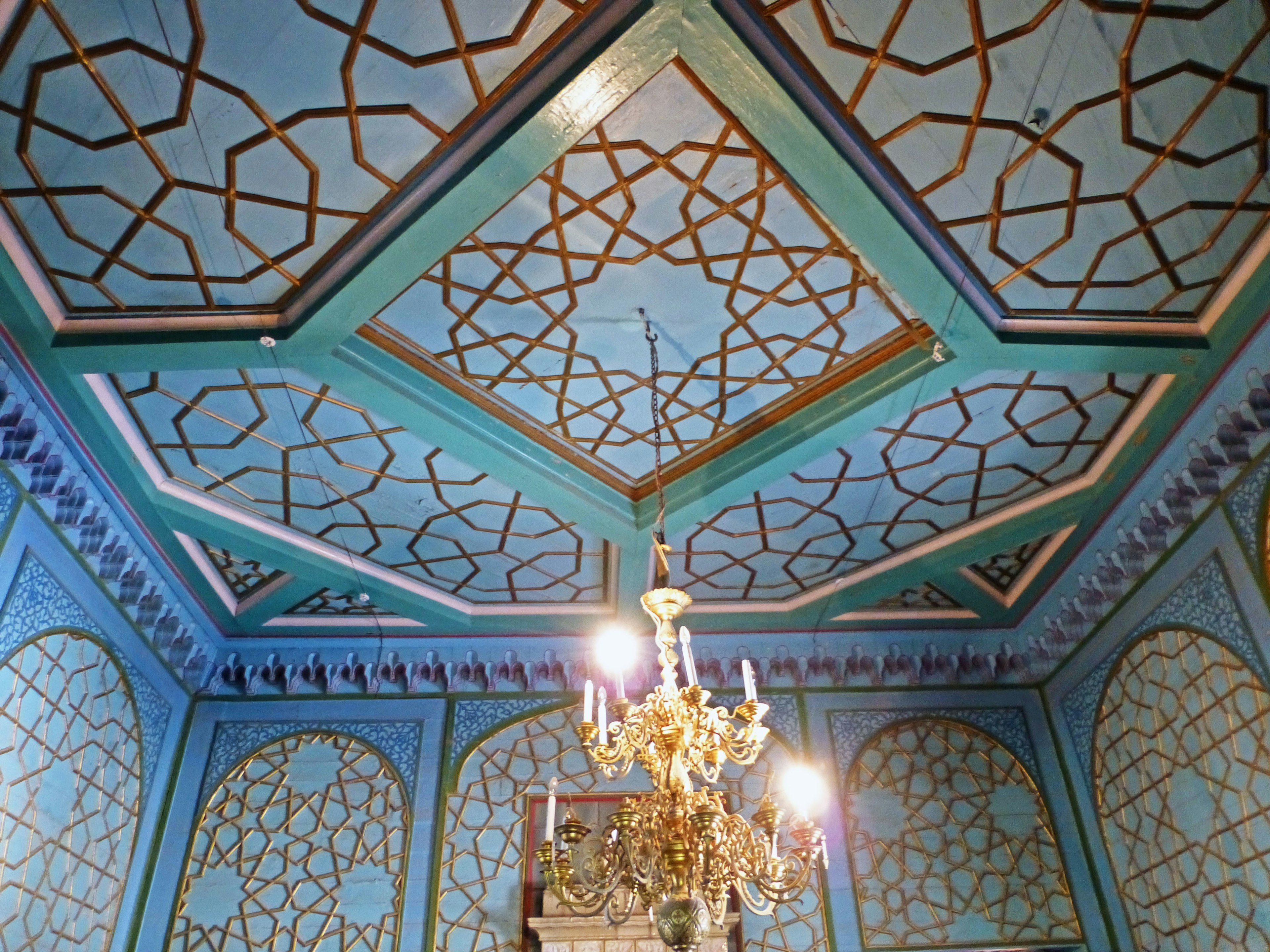 Interior de una habitación lujosa con un techo azul y decoraciones doradas