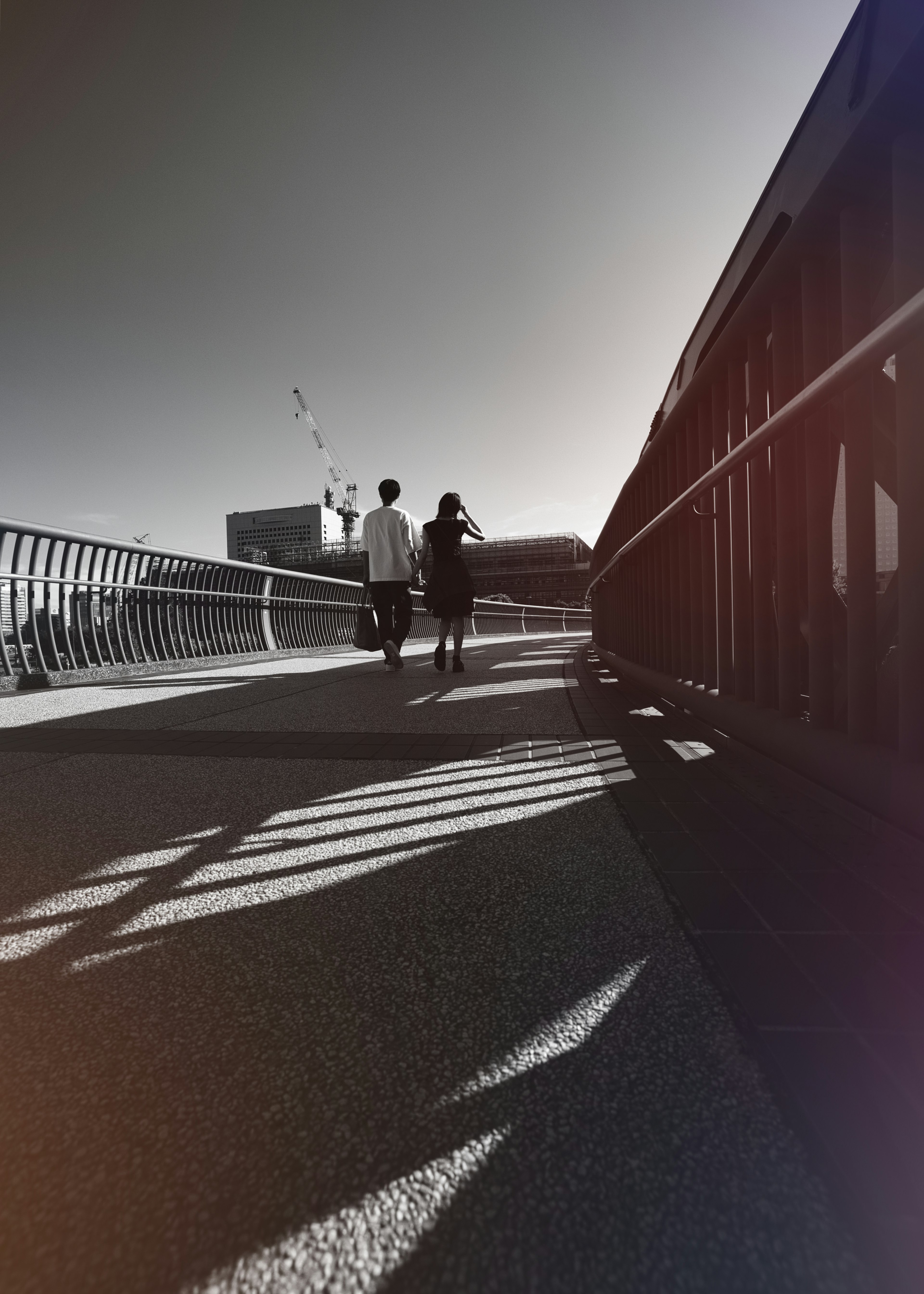 Dos personas caminando por un camino con sombras en blanco y negro