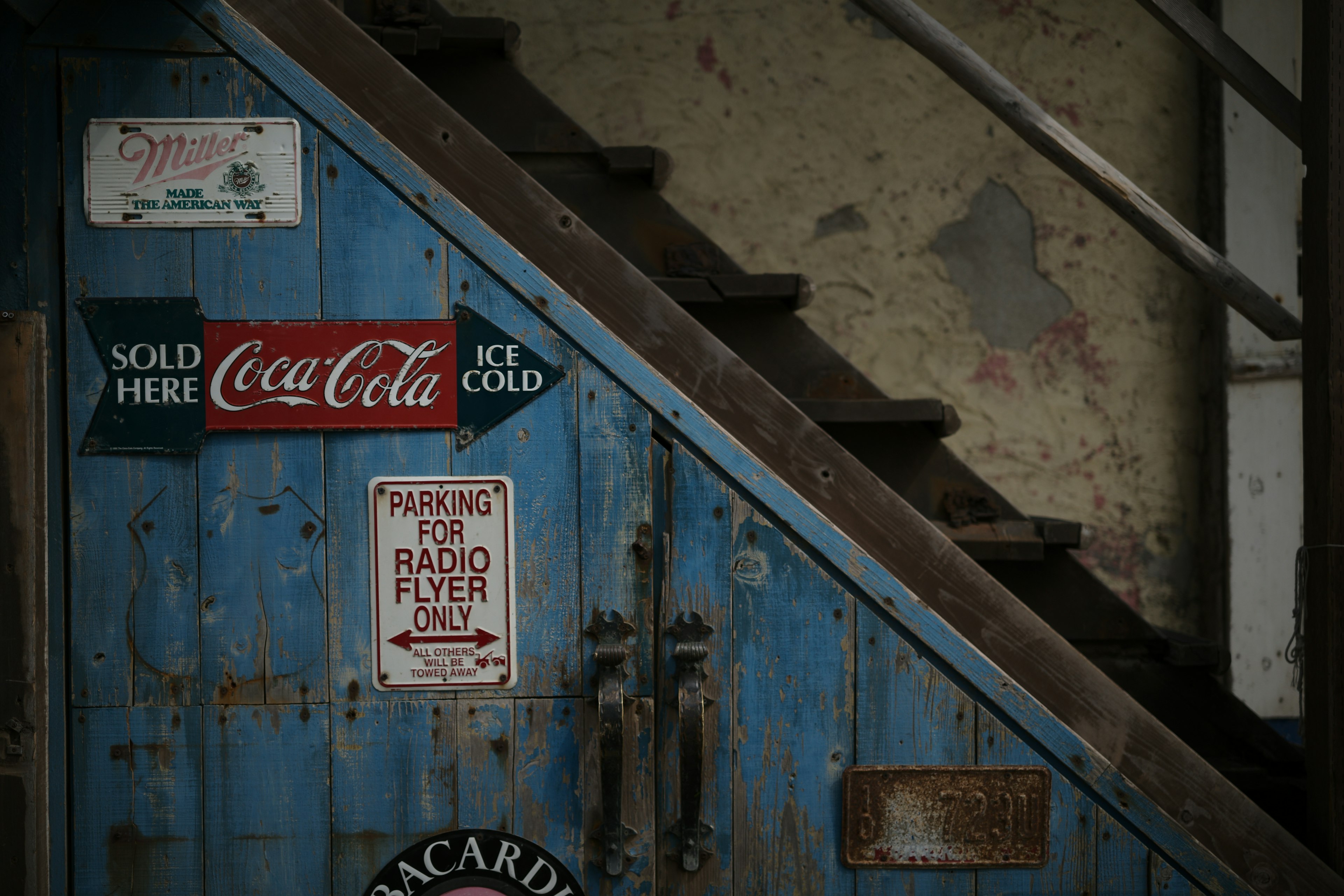 Una porta blu vintage con diverse vecchie pubblicità e una scala