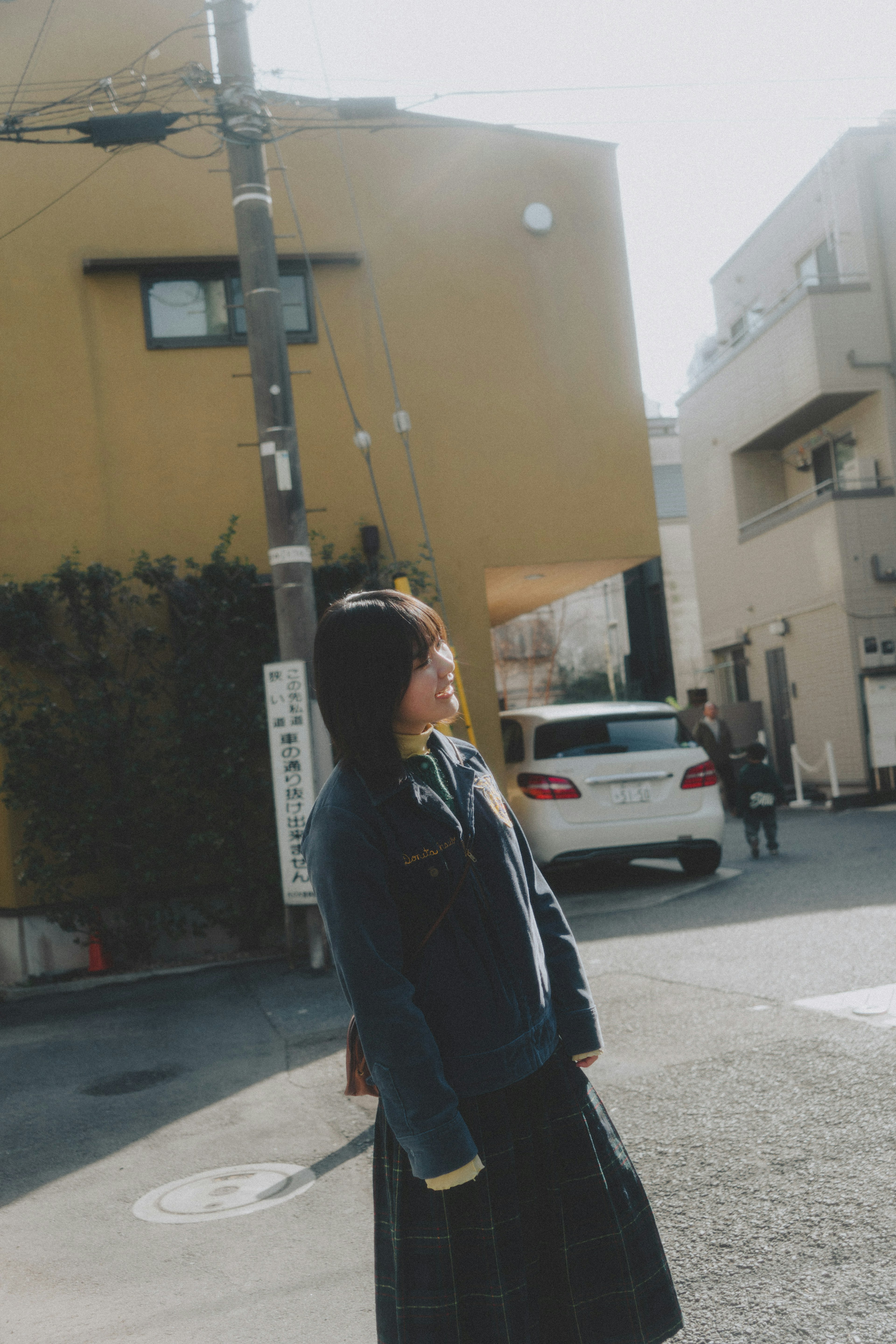 Woman standing at a street corner with distinctive buildings in the background