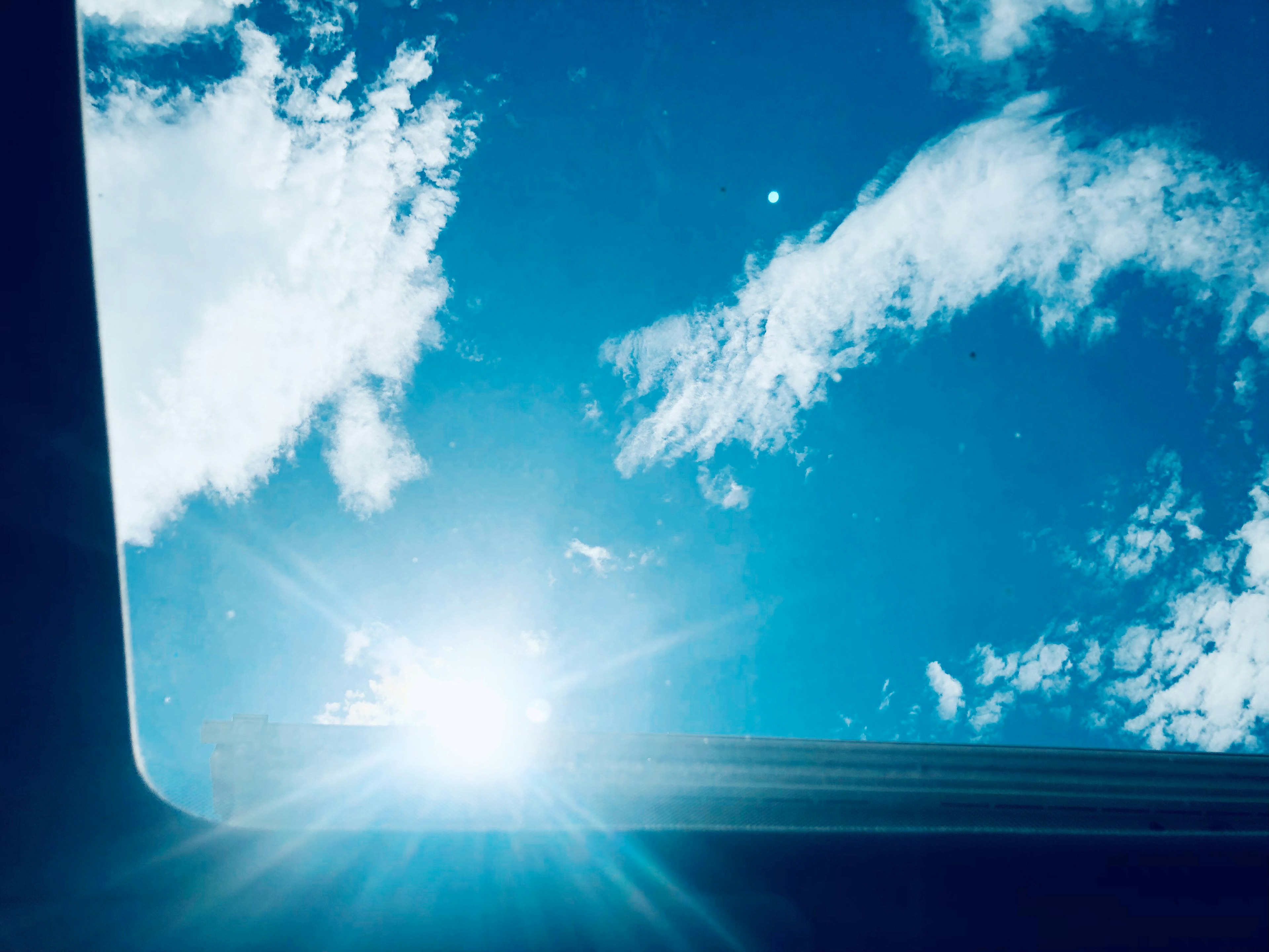 Photo d'un toit ouvrant de voiture montrant un ciel bleu et des nuages blancs