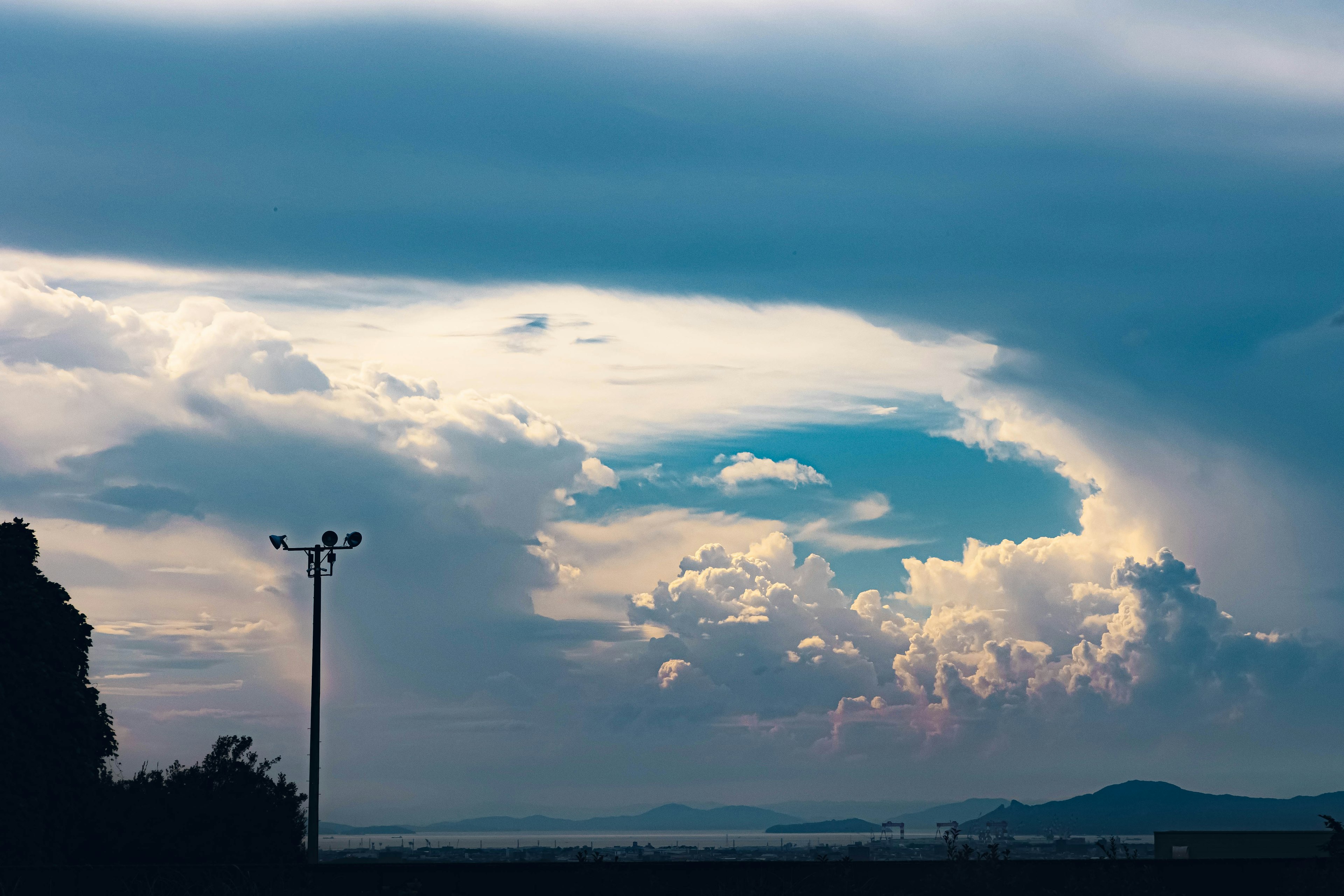 Awan berputar di langit biru dengan gunung jauh