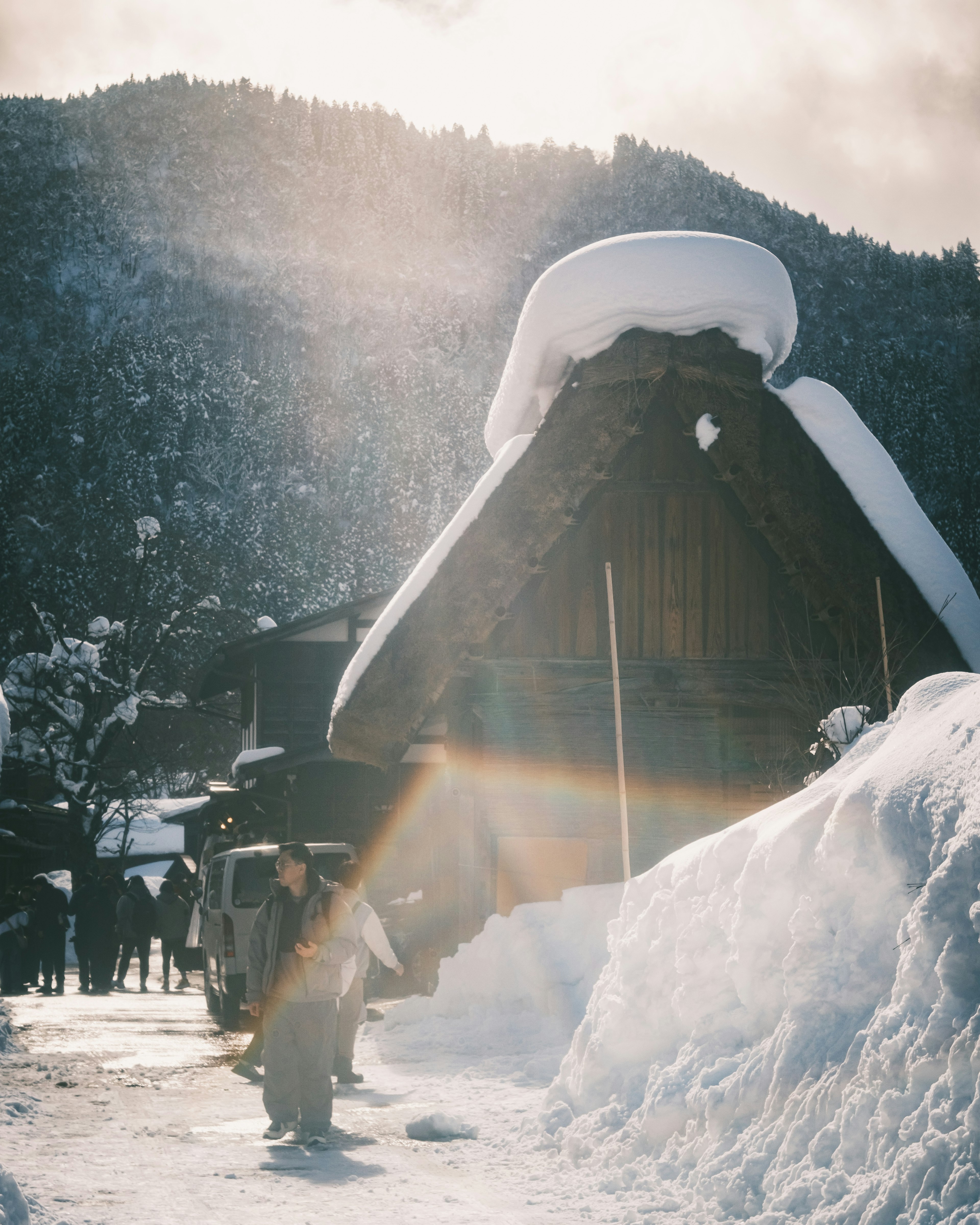 Traditionelles japanisches Gassho-zukuri-Haus, das mit Schnee bedeckt ist, mit umliegenden Bergen