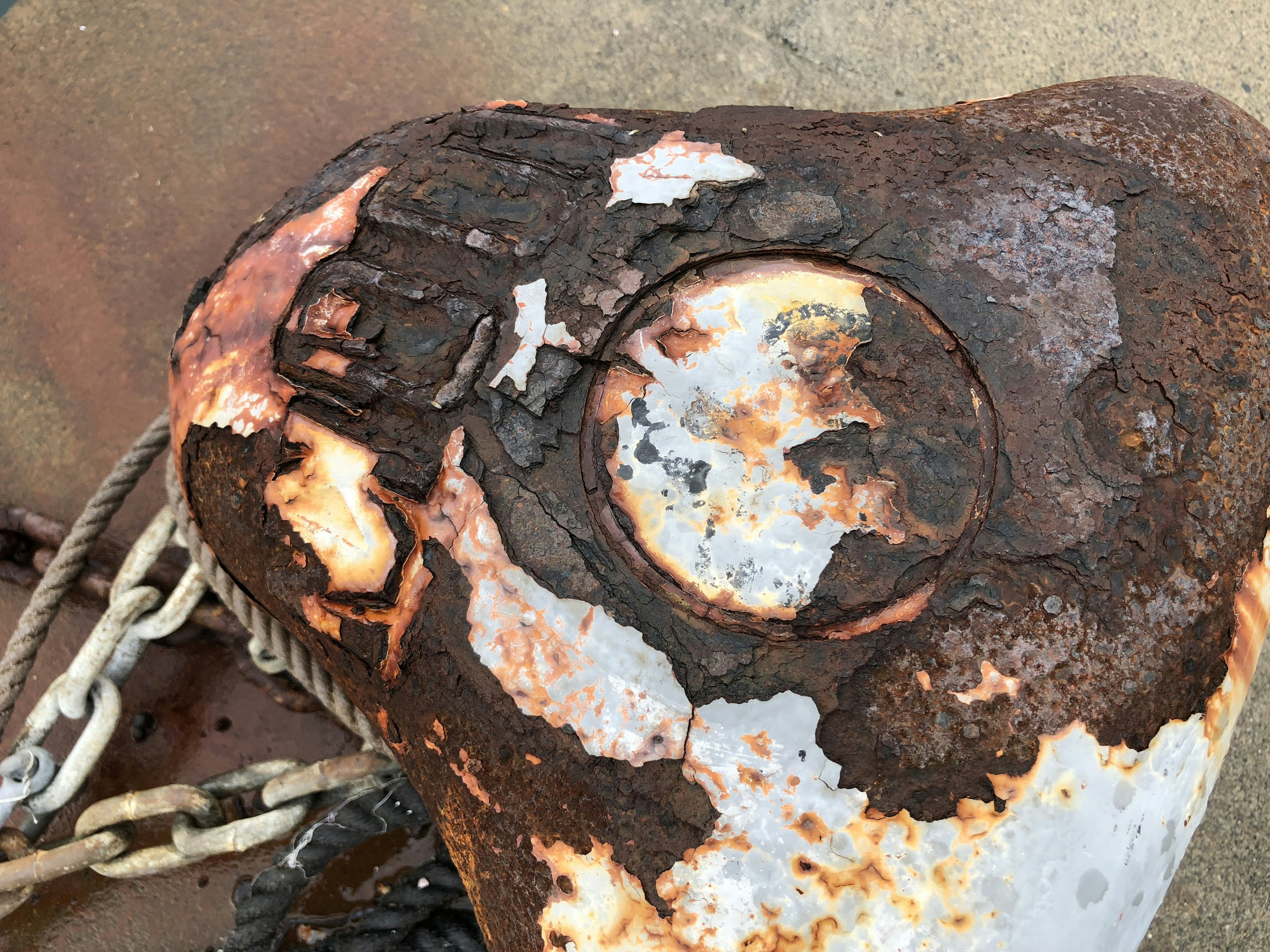 A close-up of a rusty metal anchor with a chain partially visible