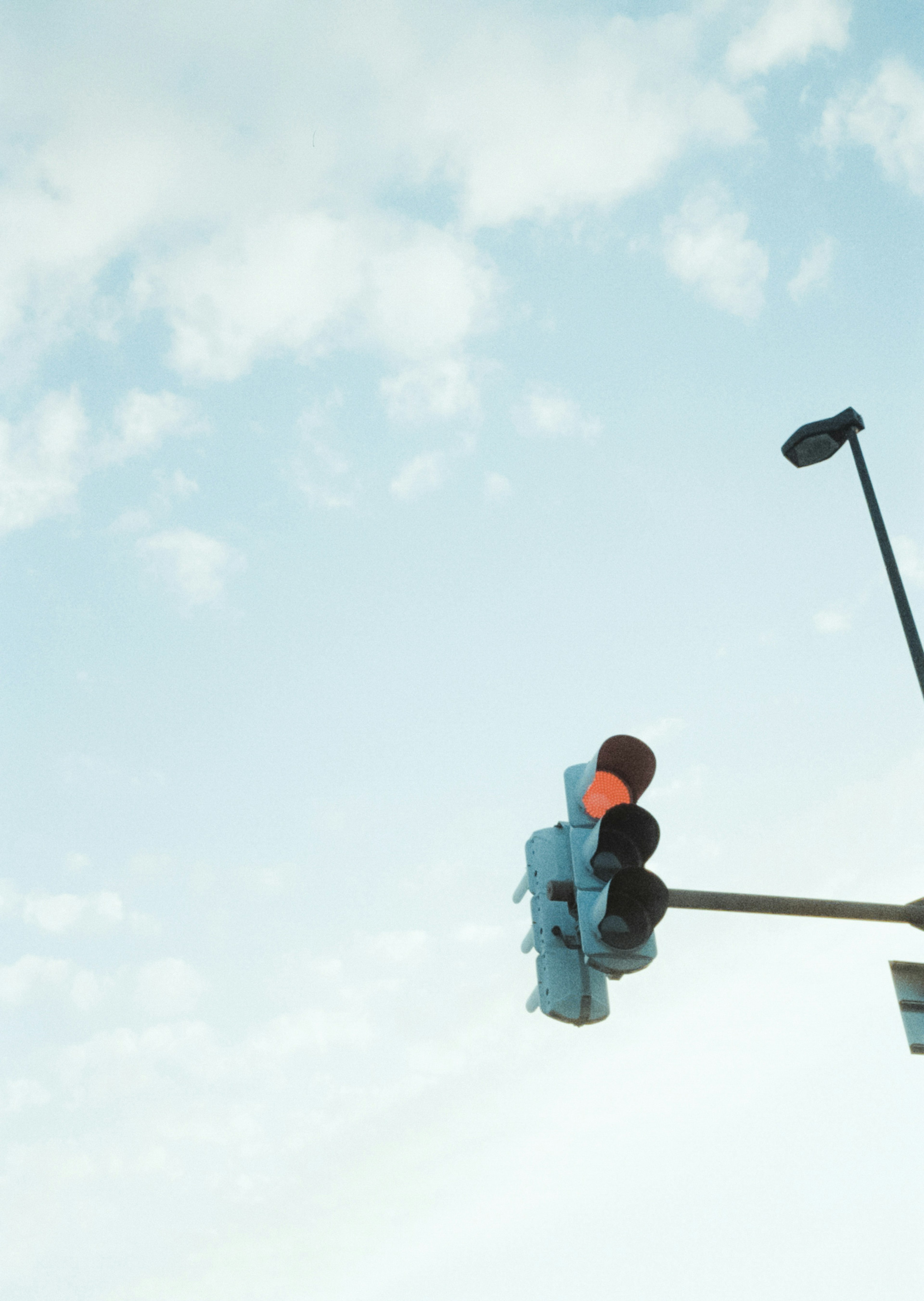 Ampel mit grünem und orangefarbenem Licht vor blauem Himmel