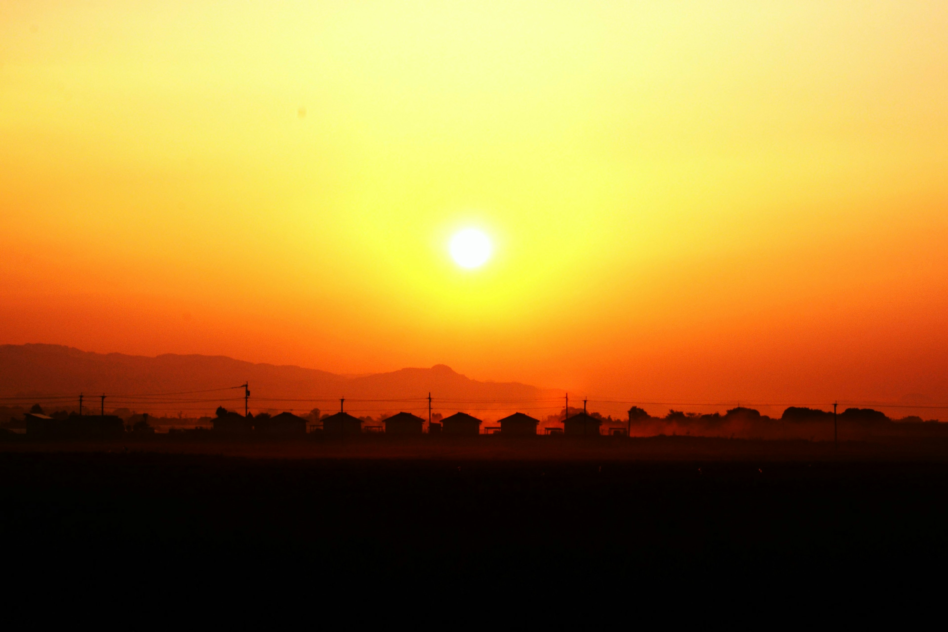 夕日が美しく照らすオレンジ色の空とシルエットの家々