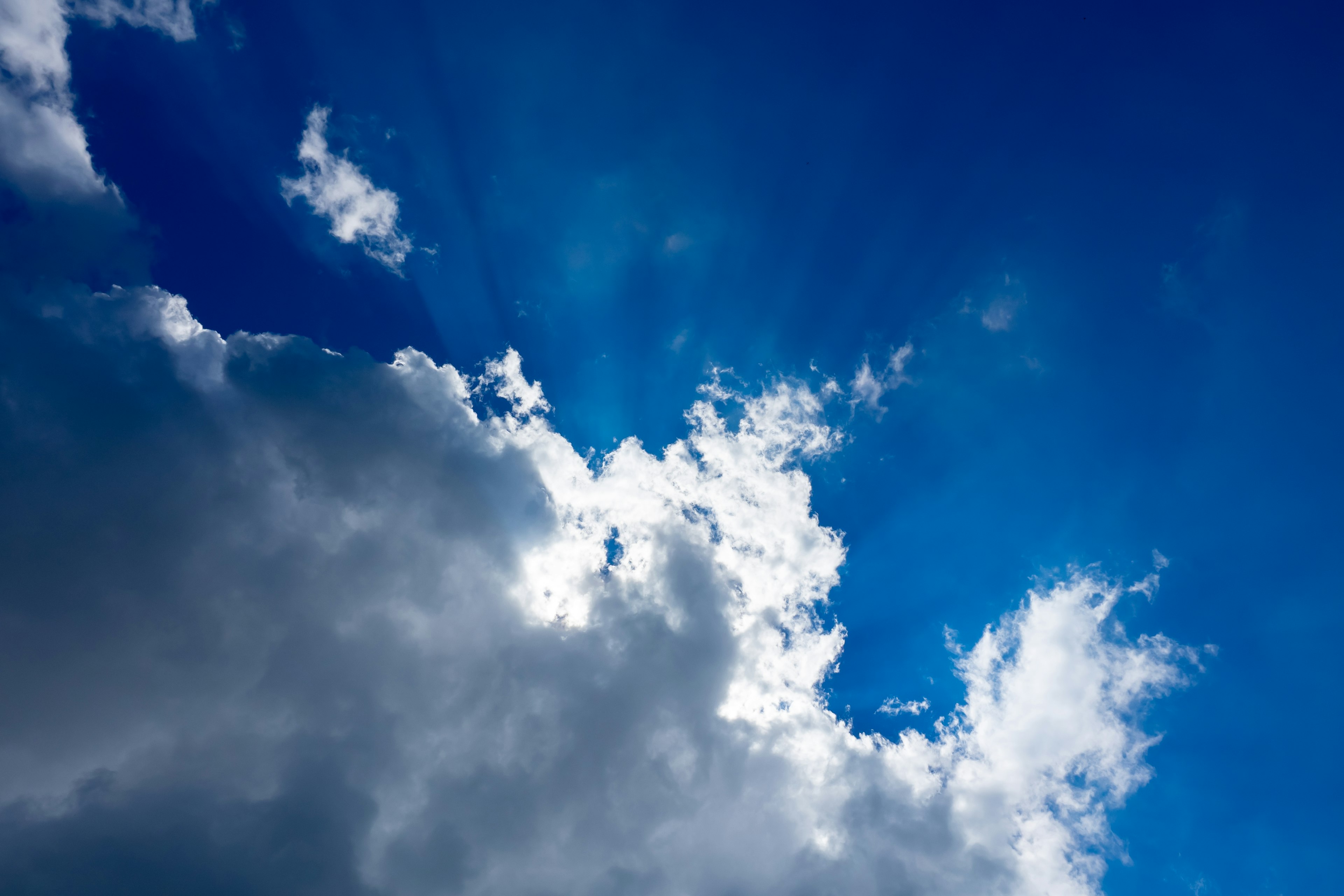 A scene of blue sky with white clouds and rays of light shining through