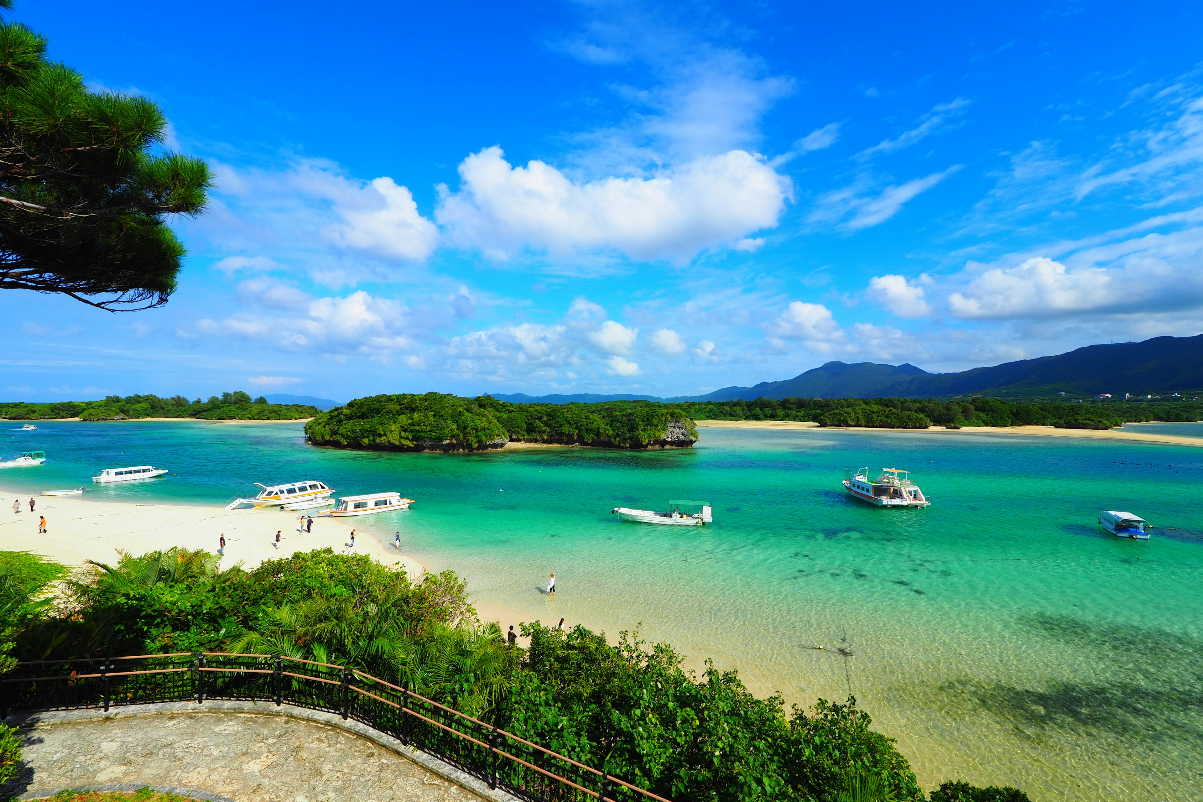 Beautiful beach and blue sea landscape with boats anchored in a calm bay clear blue sky and white clouds