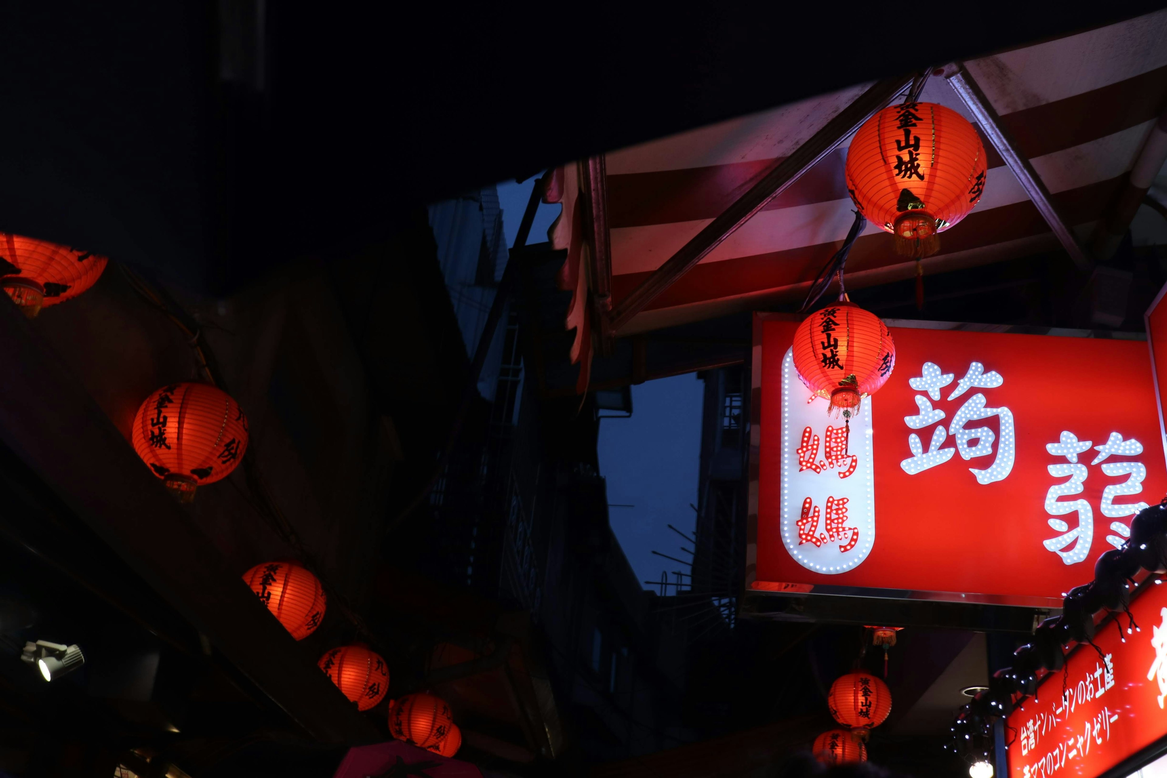 Scène nocturne avec des lanternes rouges et un panneau lumineux