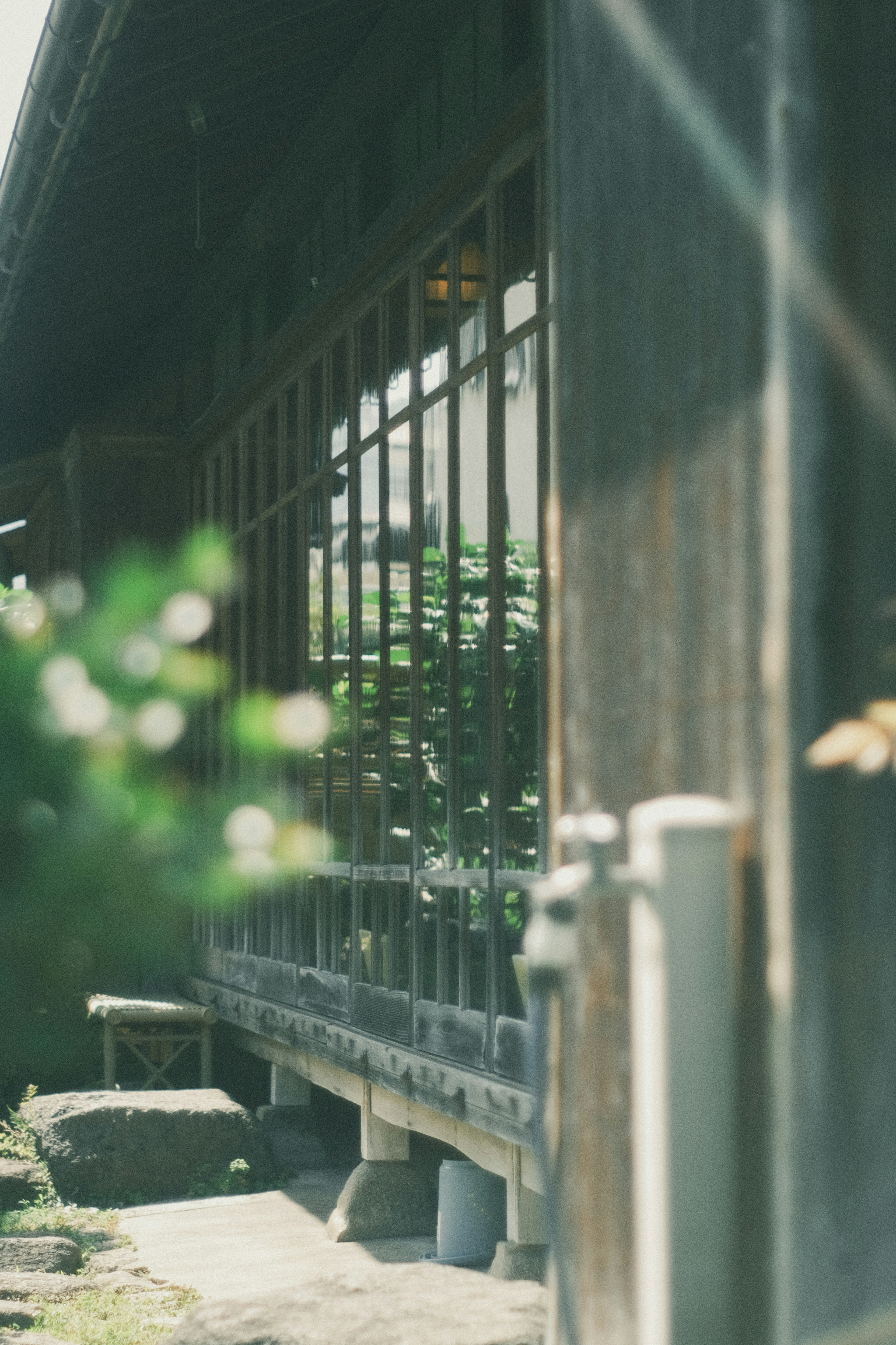 Exterior de una casa japonesa tradicional con ventanas de madera y vegetación