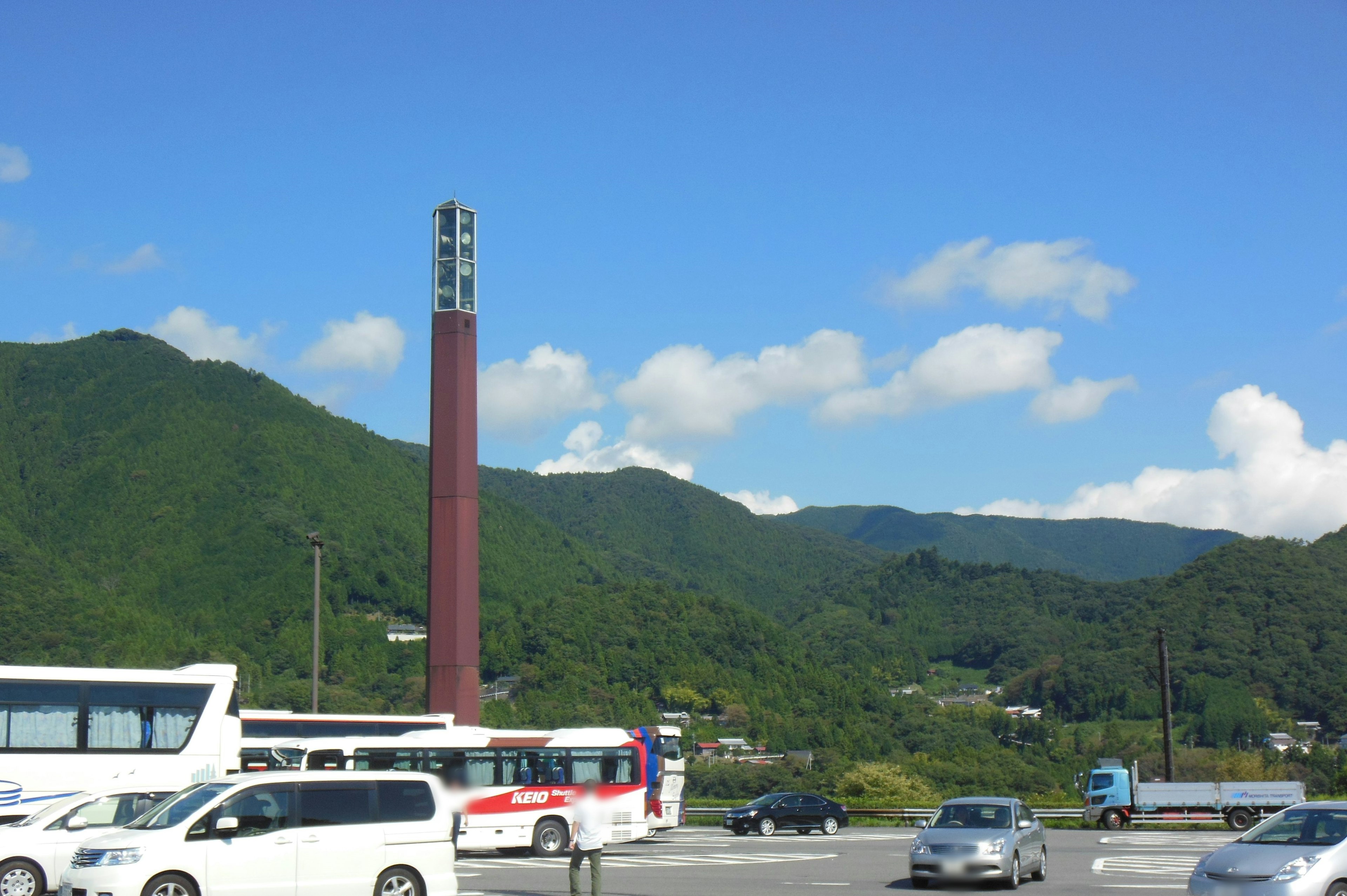 Scenic view of mountains under blue sky with vehicles in foreground