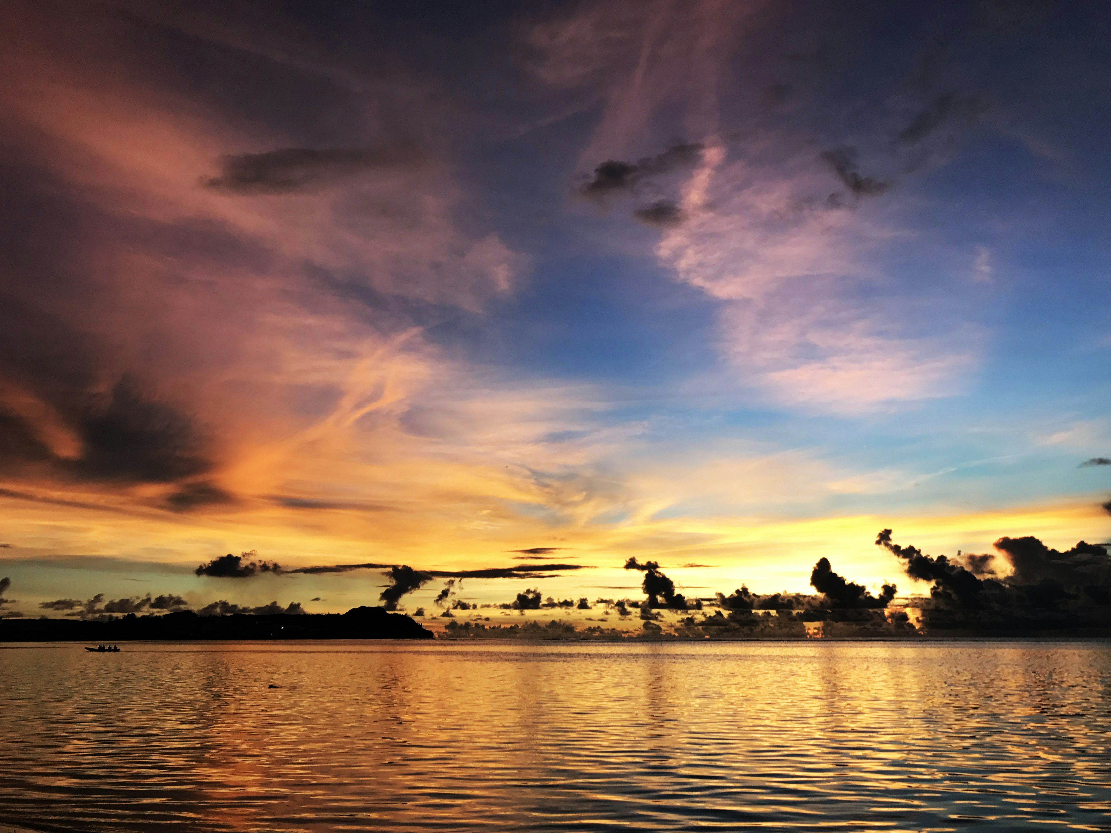 Senja berwarna-warni di atas air dengan awan cerah