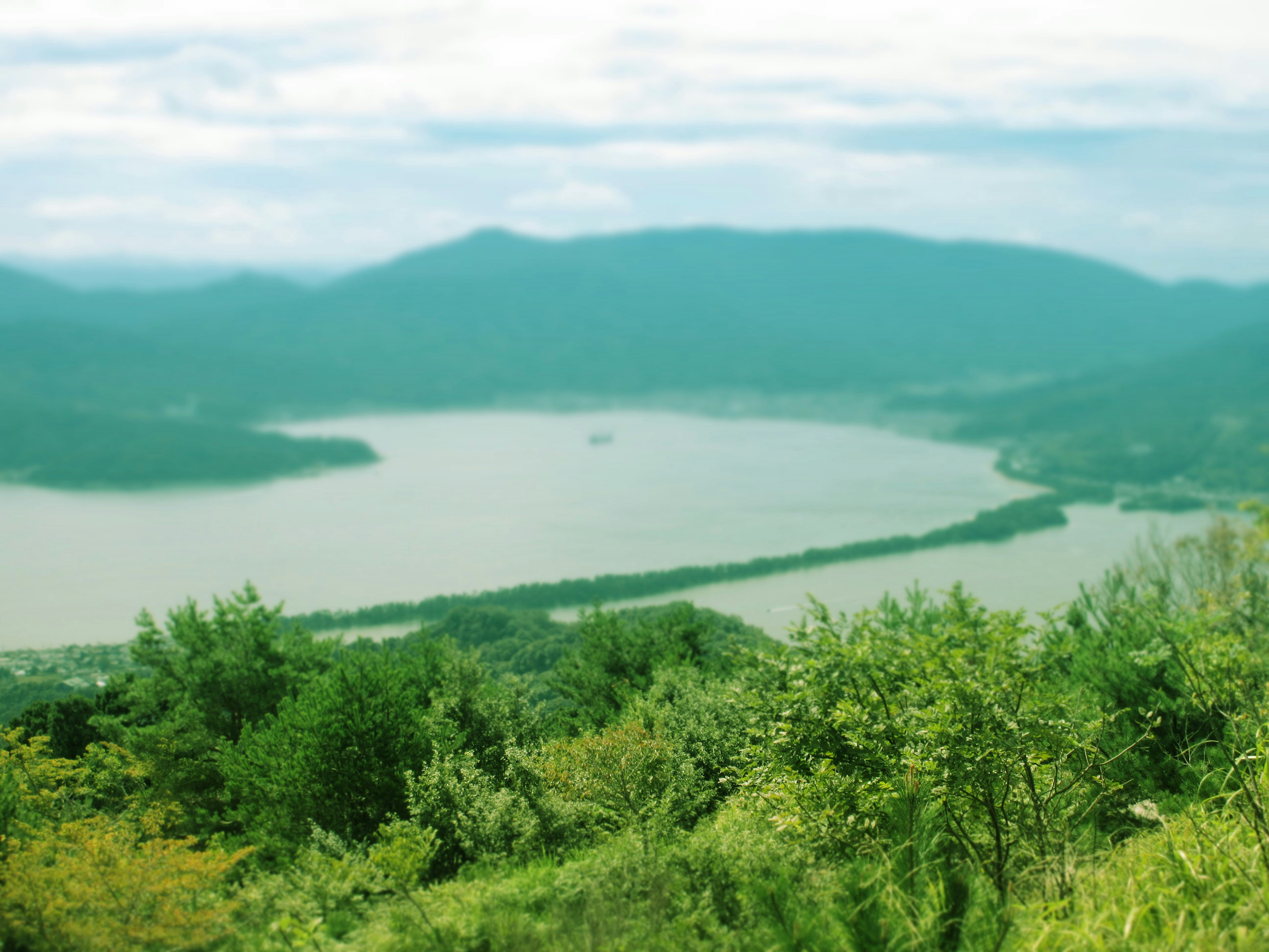 Pemandangan indah dengan danau dan pegunungan dilihat dari bukit hijau