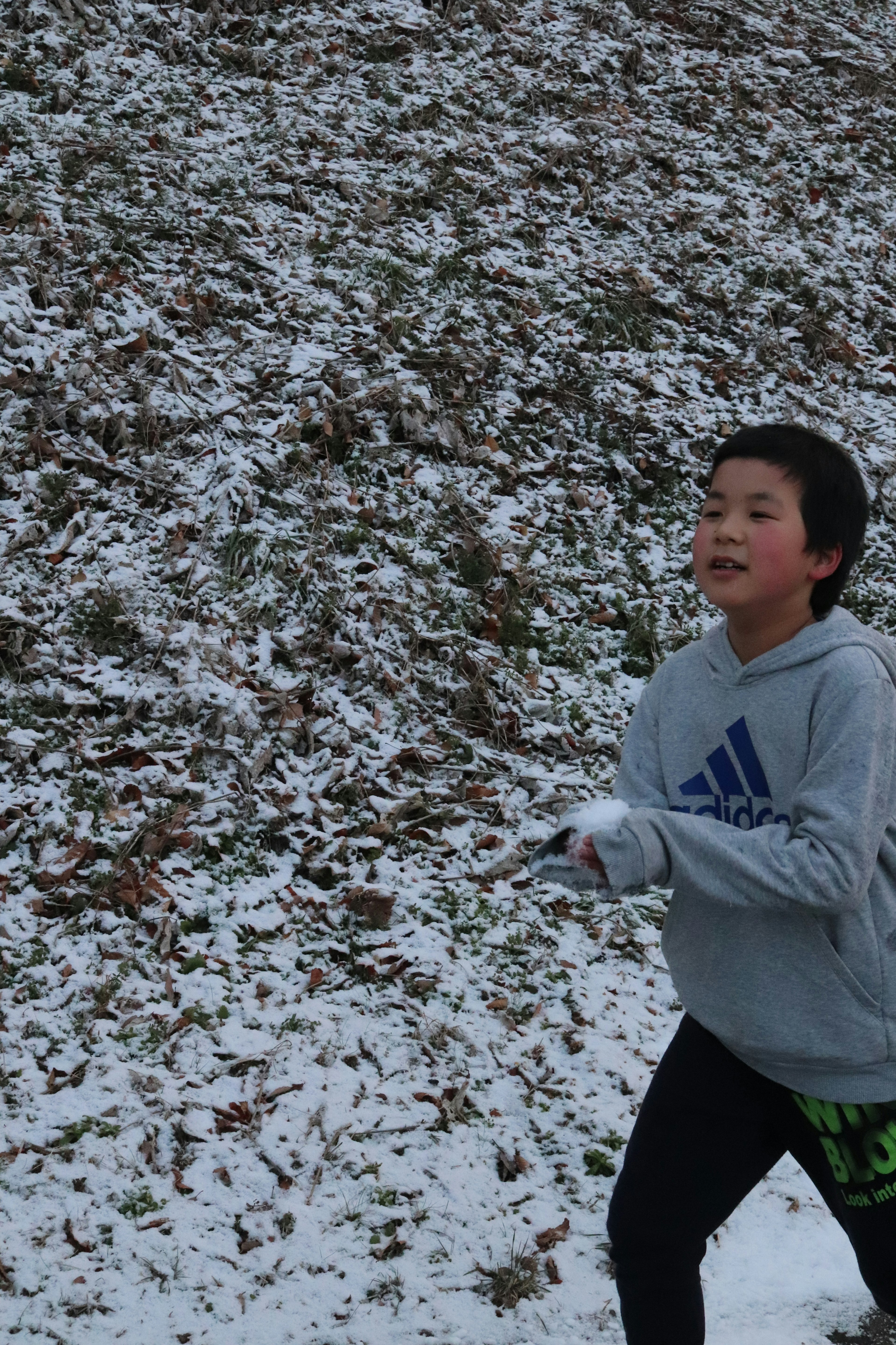 Niño corriendo en la nieve con una sudadera gris