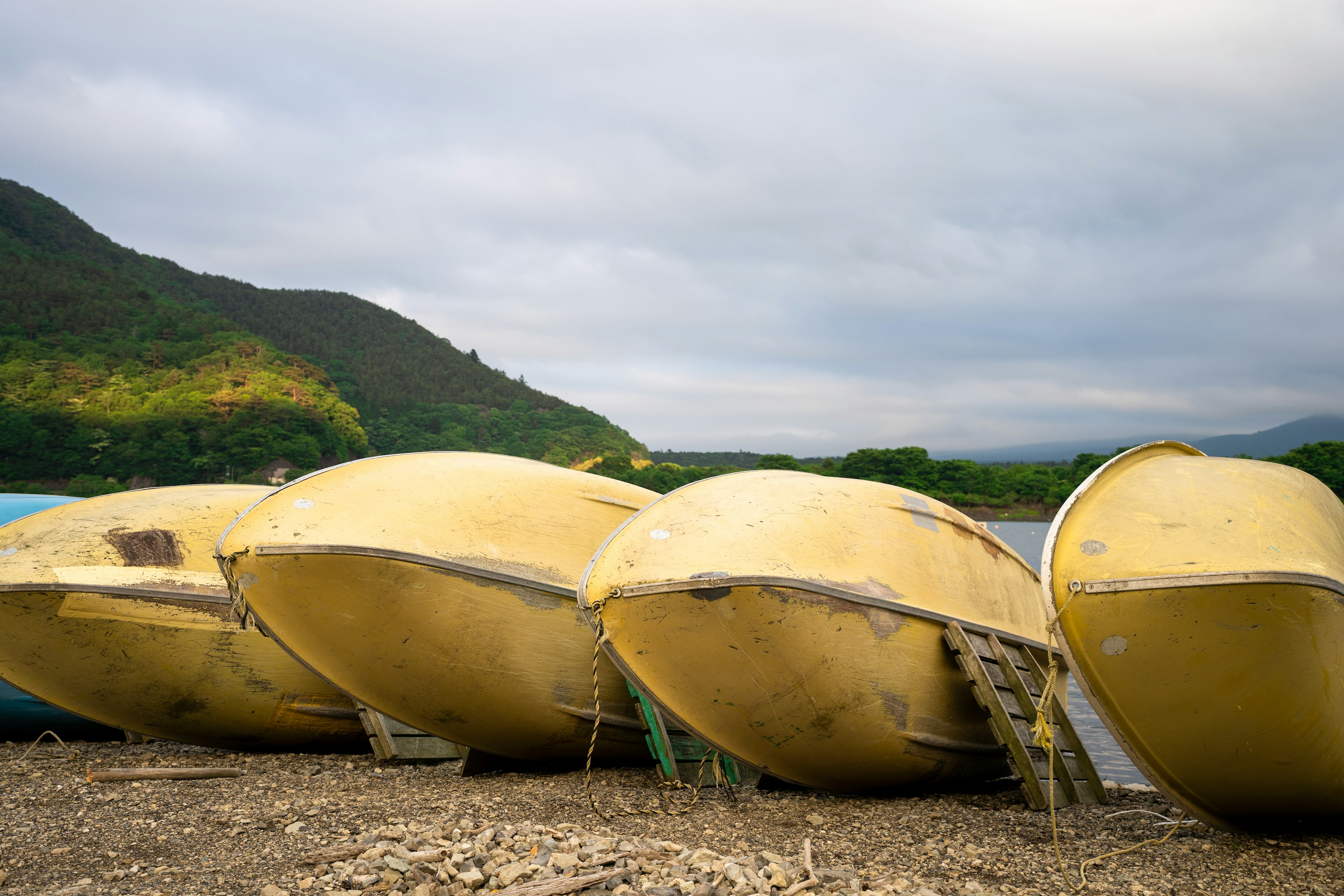 Row of yellow boats on a gravel shore with mountains in the background