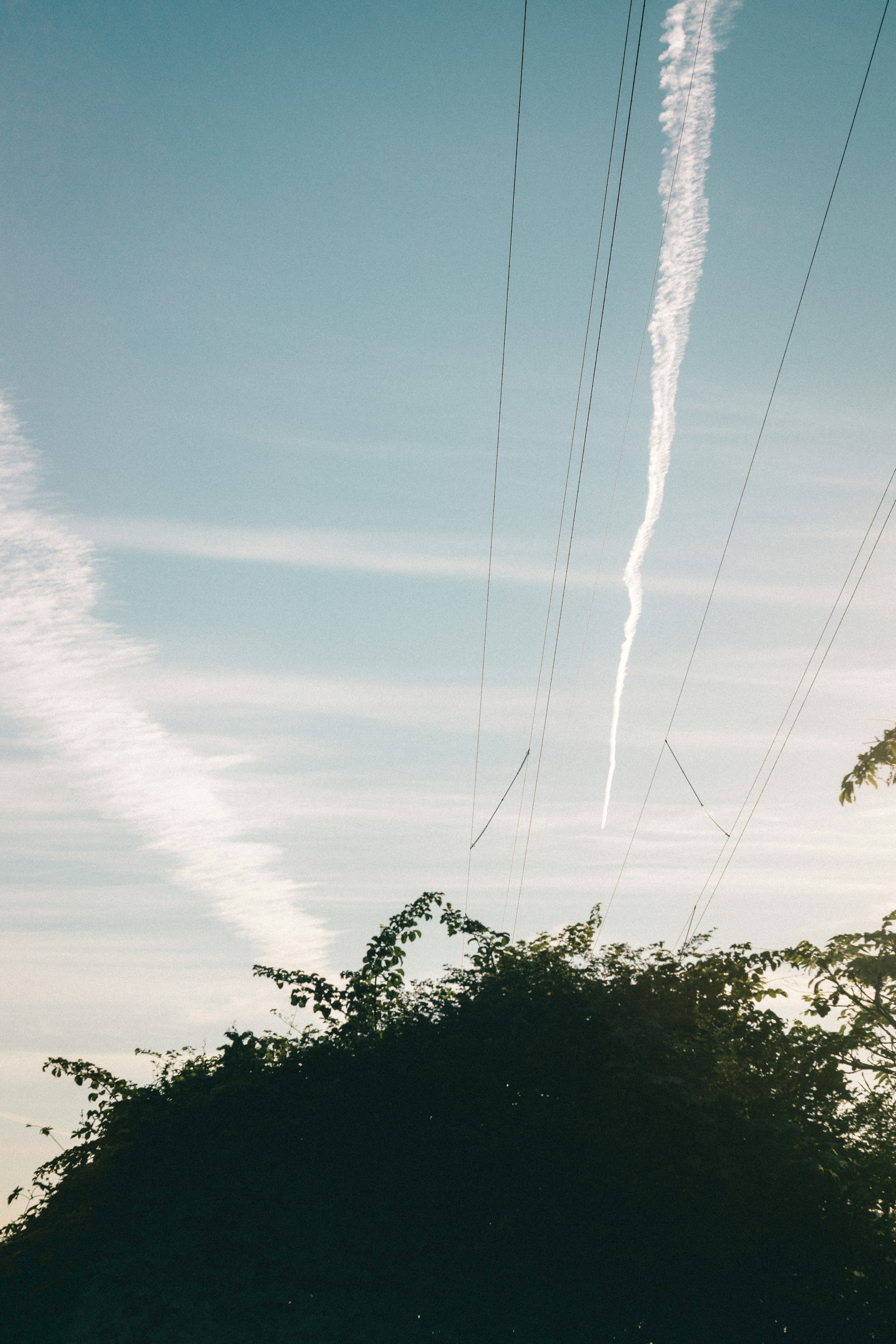 Vue pittoresque d'un ciel bleu avec des traînées nuageuses blanches et des lignes électriques