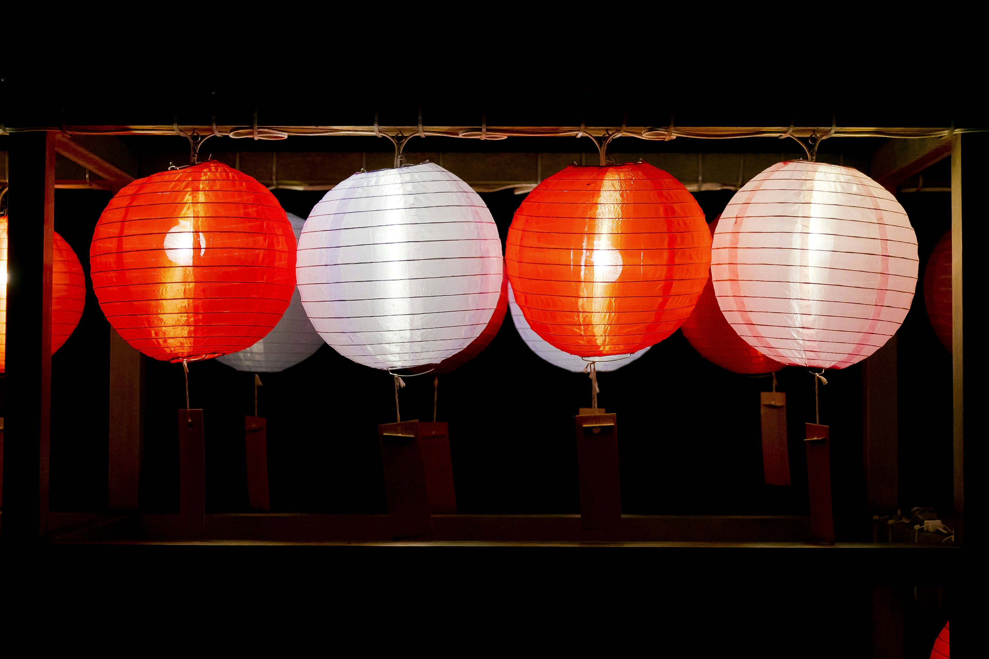 Row of red and white lanterns illuminated at night