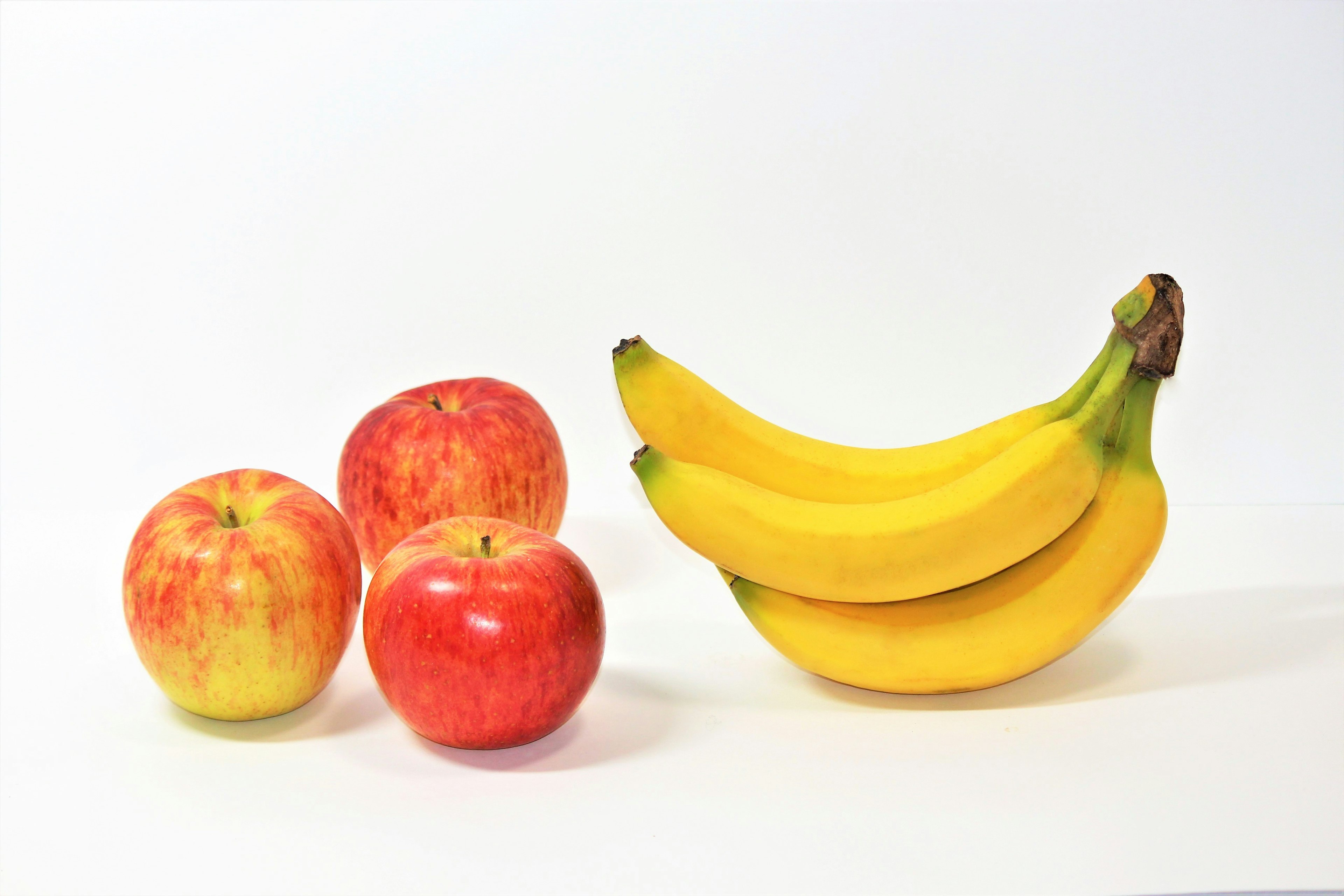 Una combinazione di mele rosse e banane gialle su uno sfondo bianco