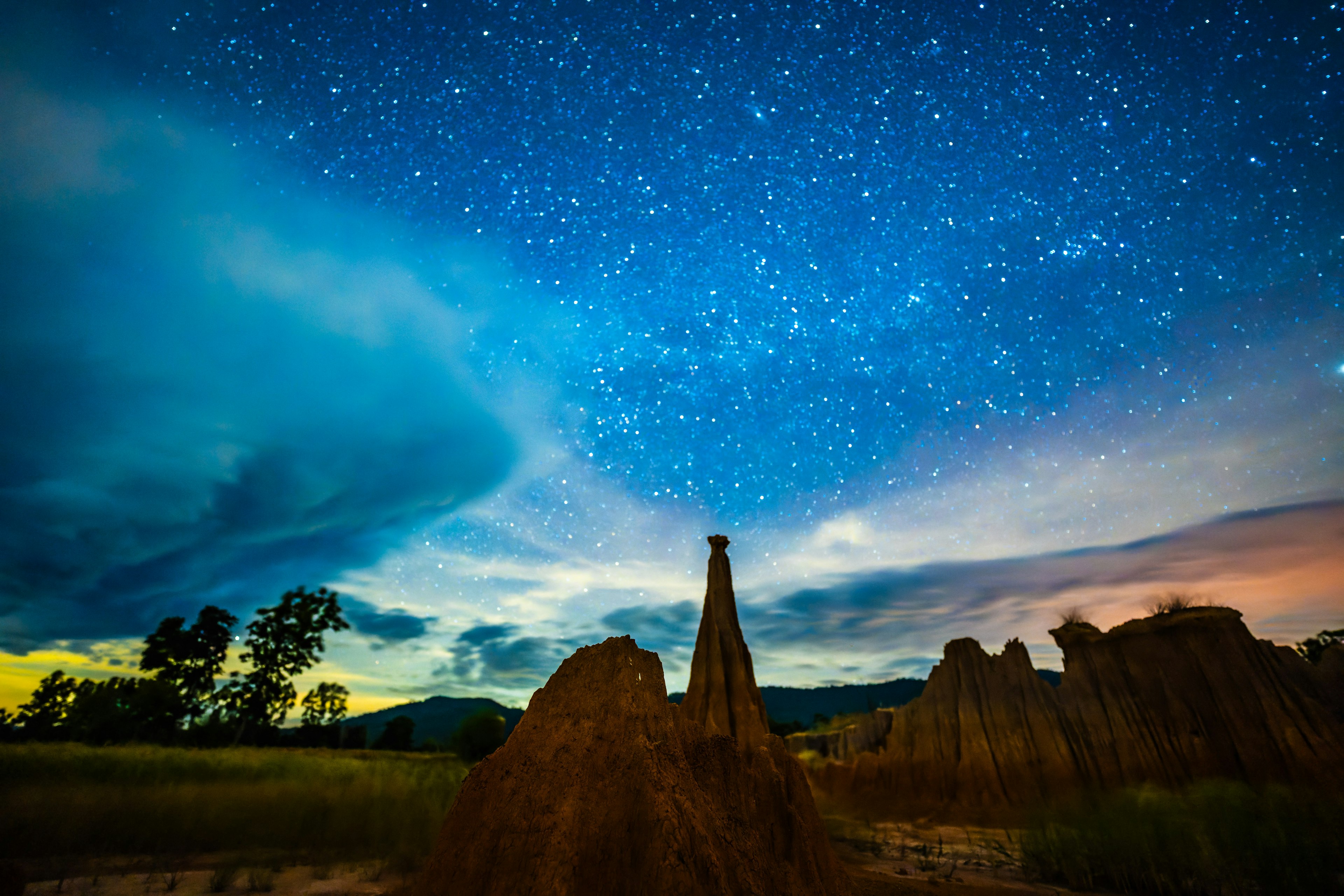 Starry night sky over unique earthen formations