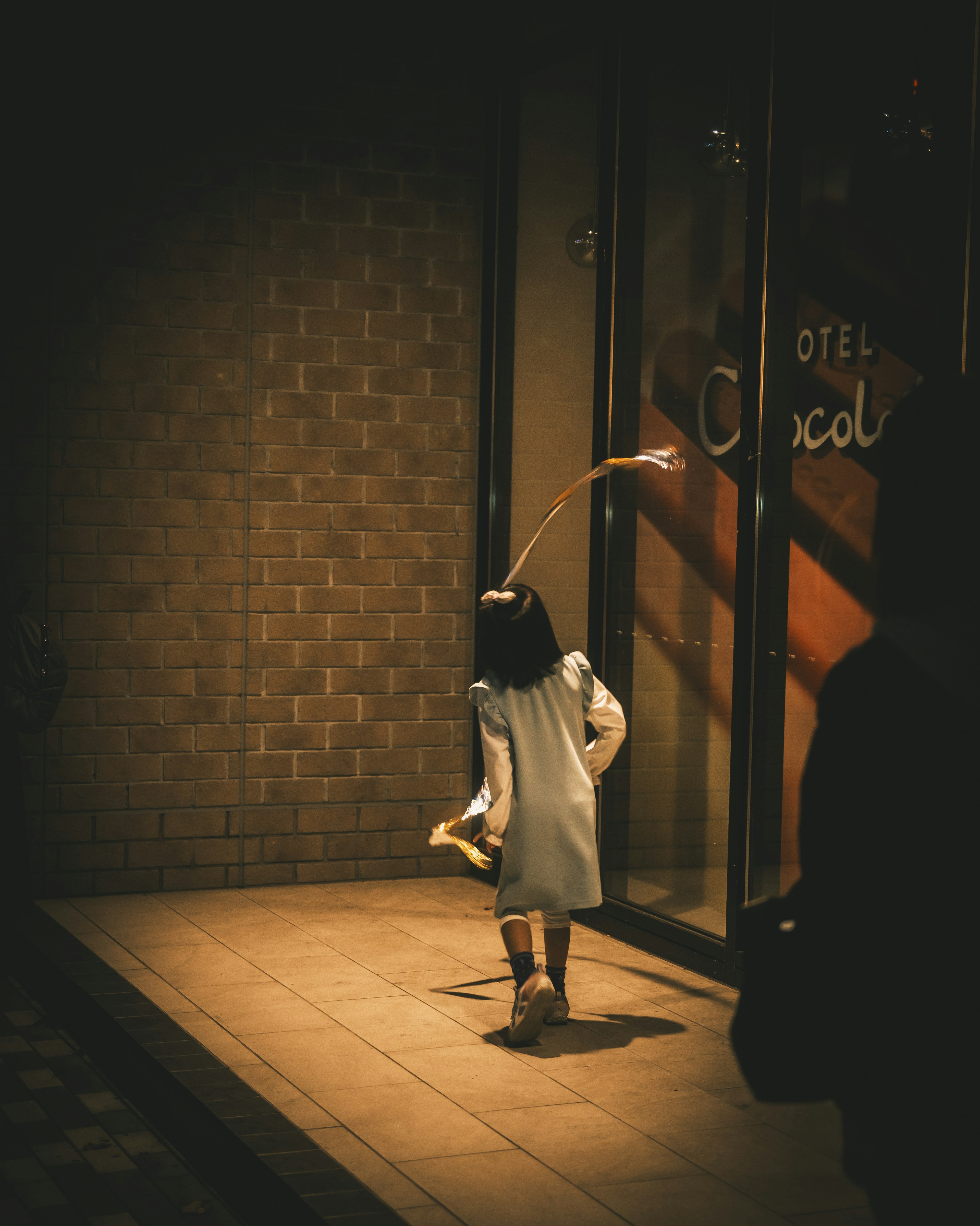 A child walking on a dimly lit street wearing a white dress