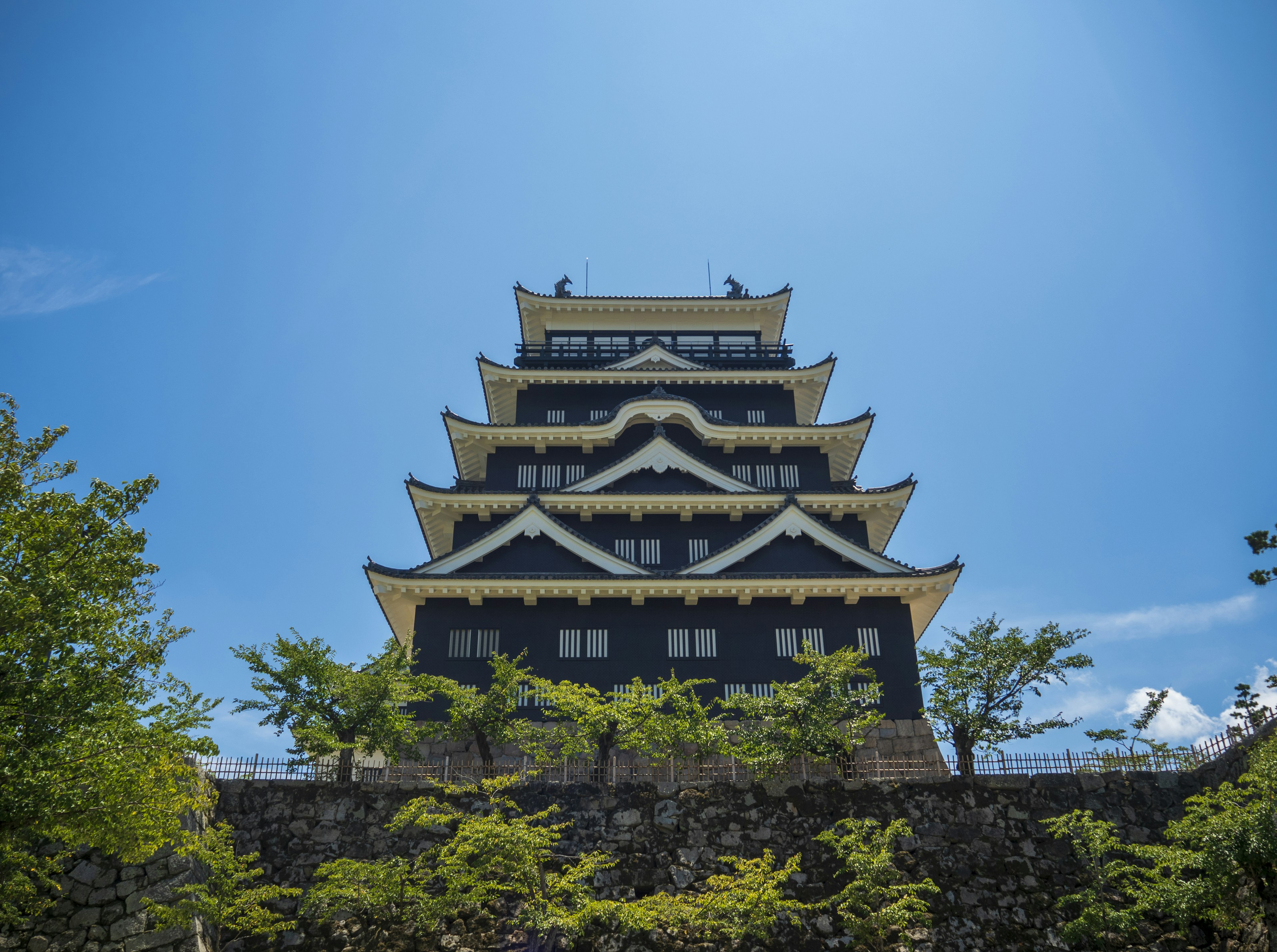 Ein fünfstöckiger Schloss-Turm mit schwarzer Fassade unter einem klaren blauen Himmel