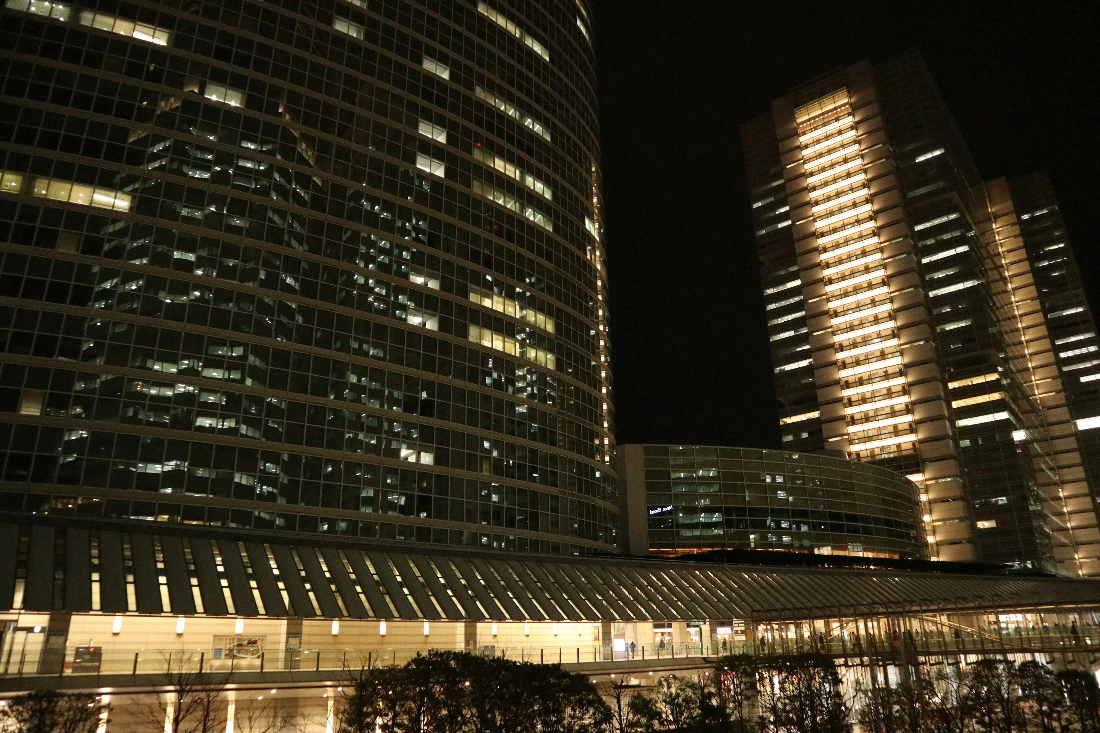 Night cityscape featuring illuminated skyscrapers with reflective glass