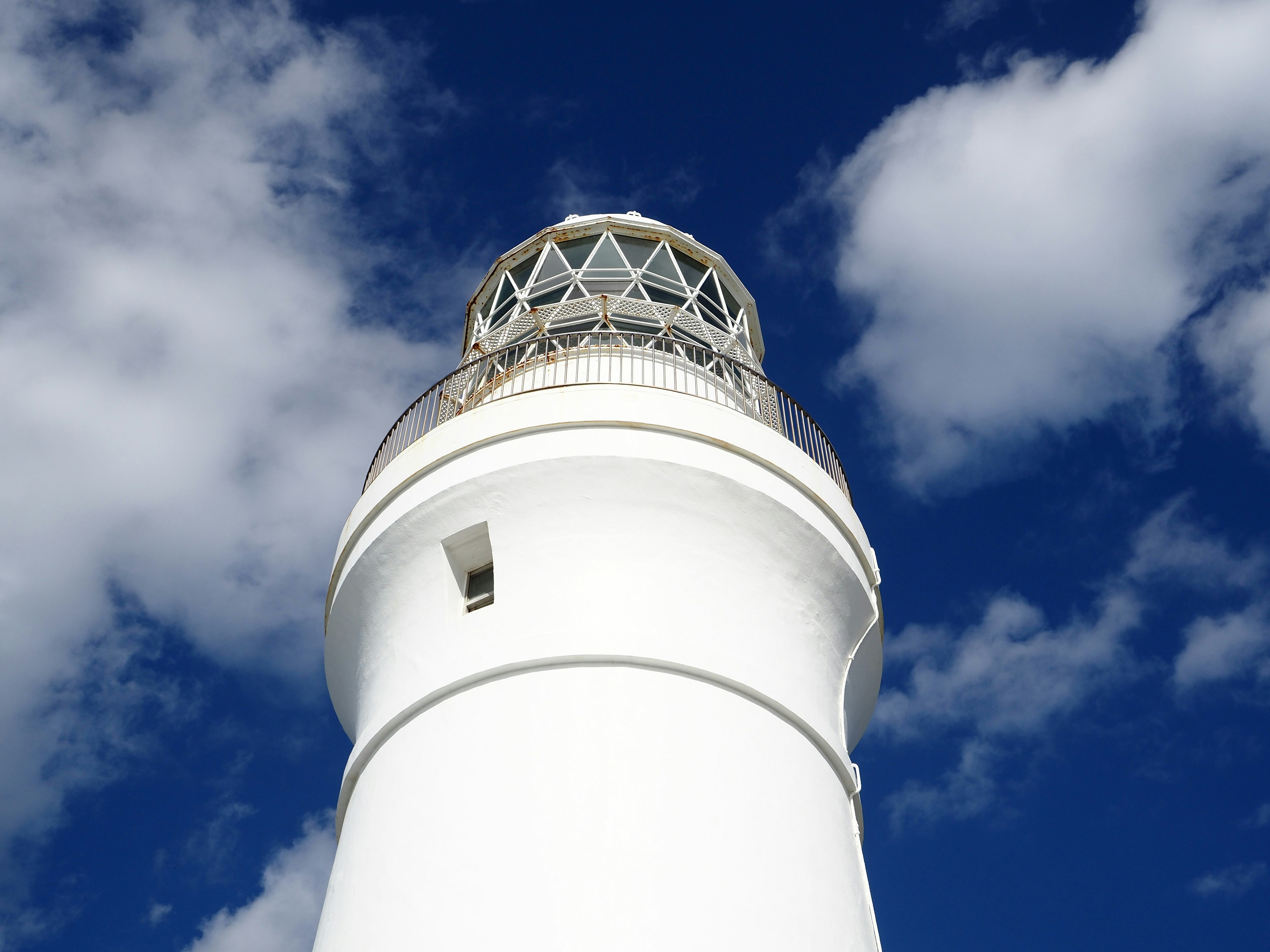 Close-up of a white lighthouse under a blue sky