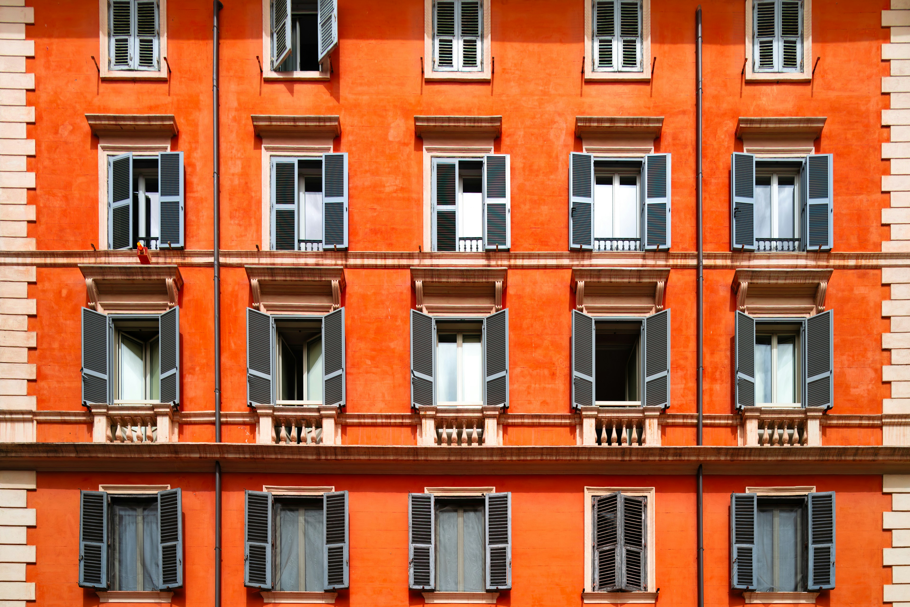 Fachada de un edificio naranja con ventanas y persianas