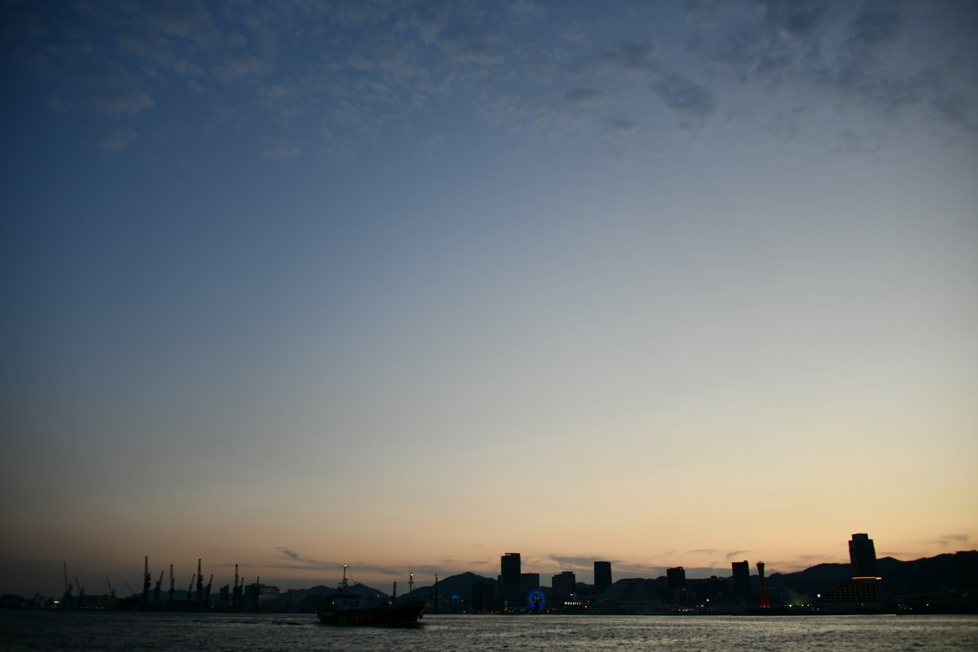 夕暮れ時の海と都市のシルエットが見える風景