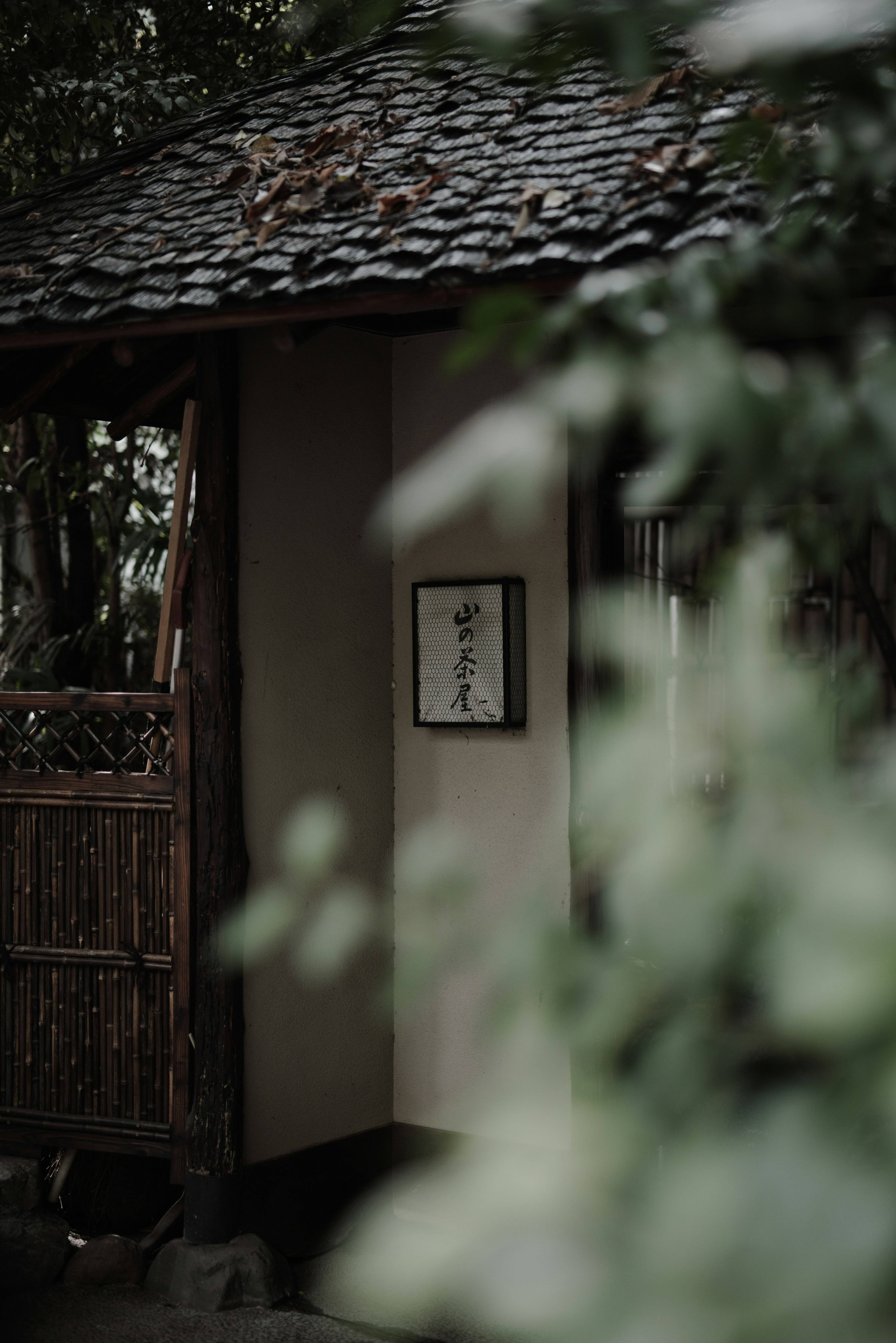 Small building exterior surrounded by greenery with a thatched roof