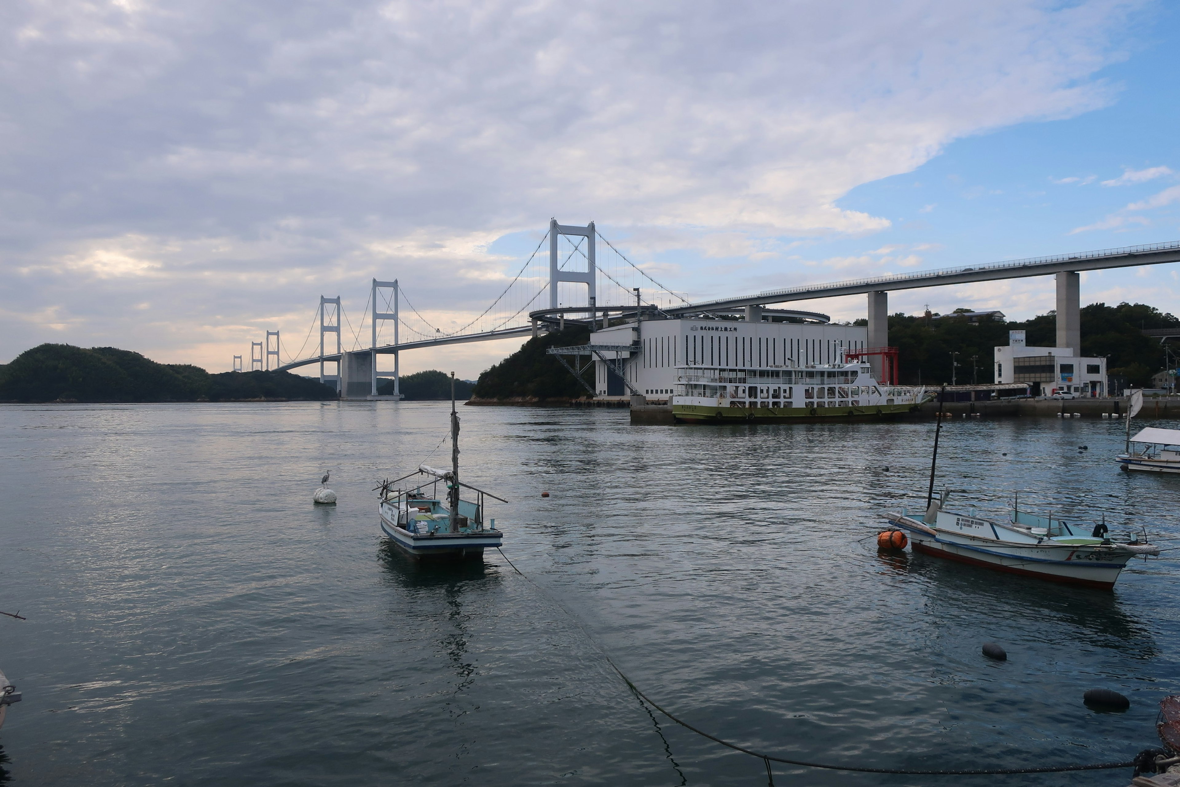 Una vista escénica de pequeños barcos en el agua con un puente al fondo