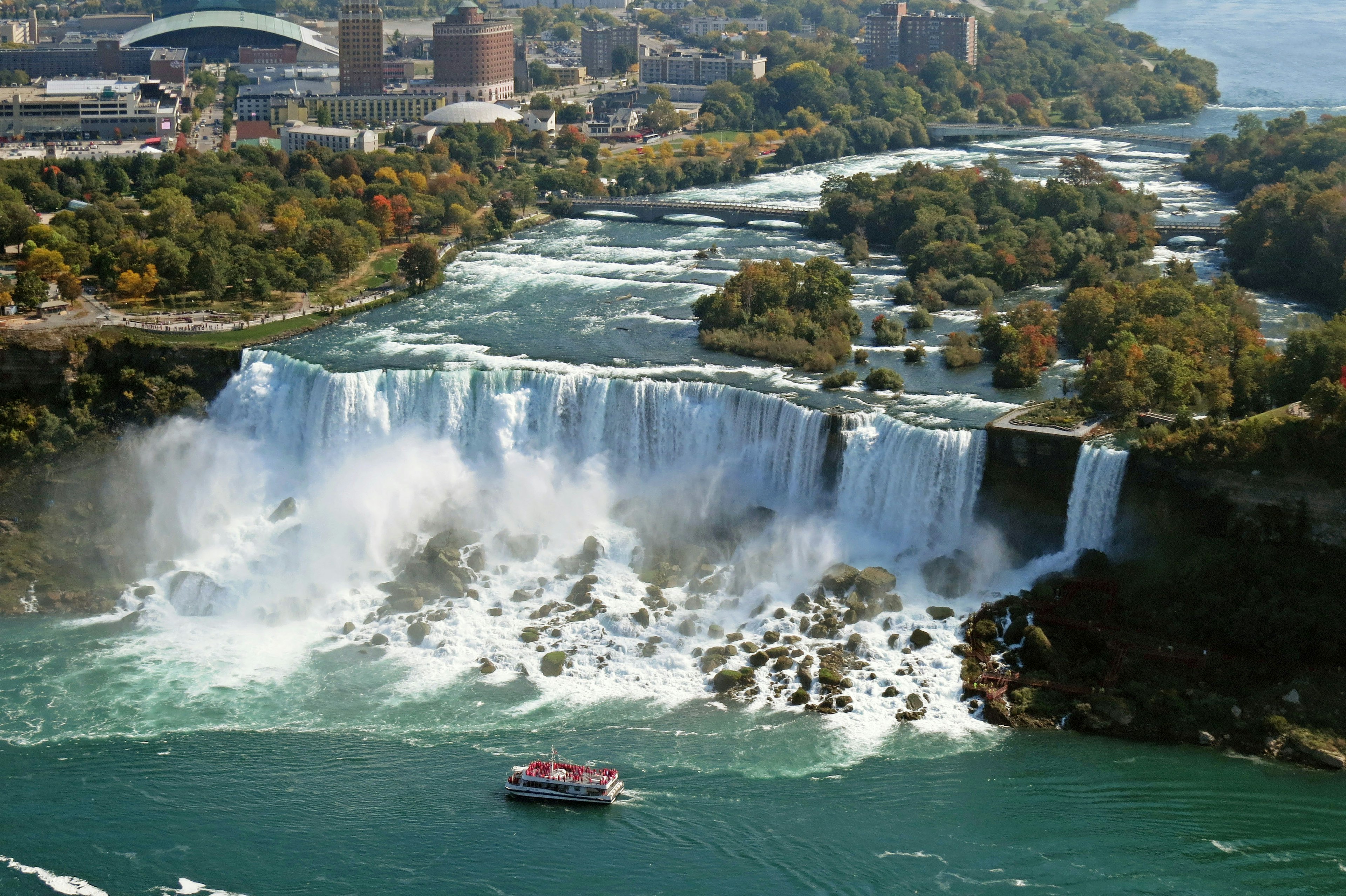 Luftaufnahme der Niagarafälle mit einem Boot in der Nähe der Fälle lebendige grüne Bäume und blaues Wasser