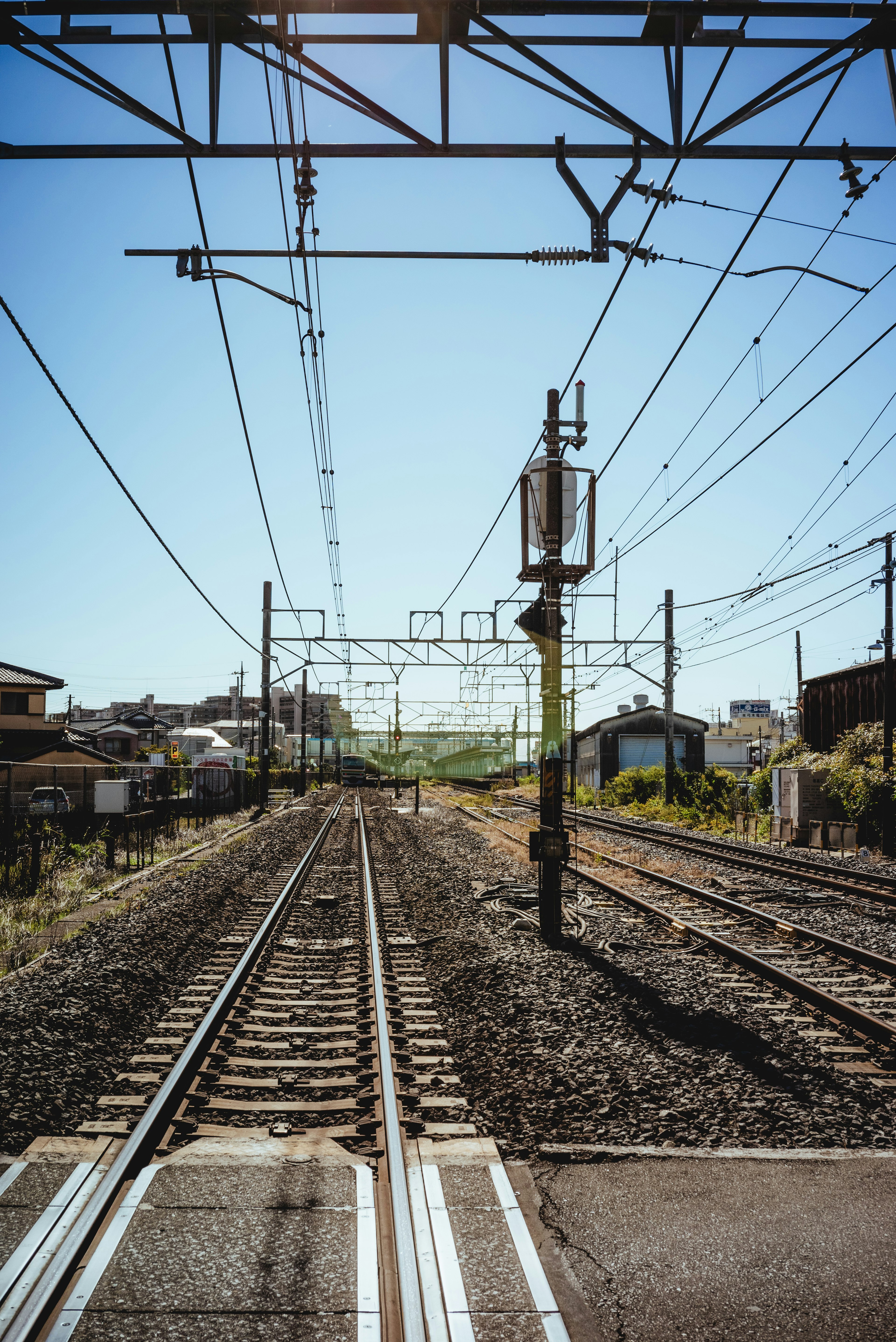 Eisenbahngleise mit Oberleitungen und klarem Himmel