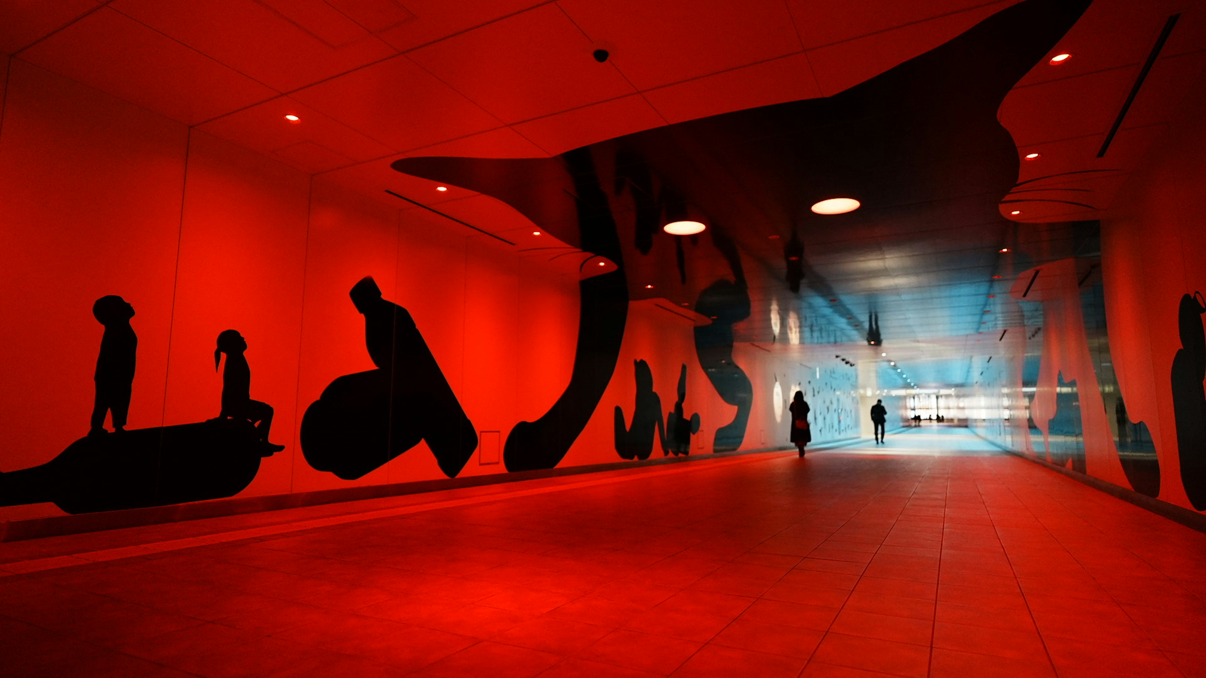 Tunnel avec silhouettes murales rouges et éclairage bleu