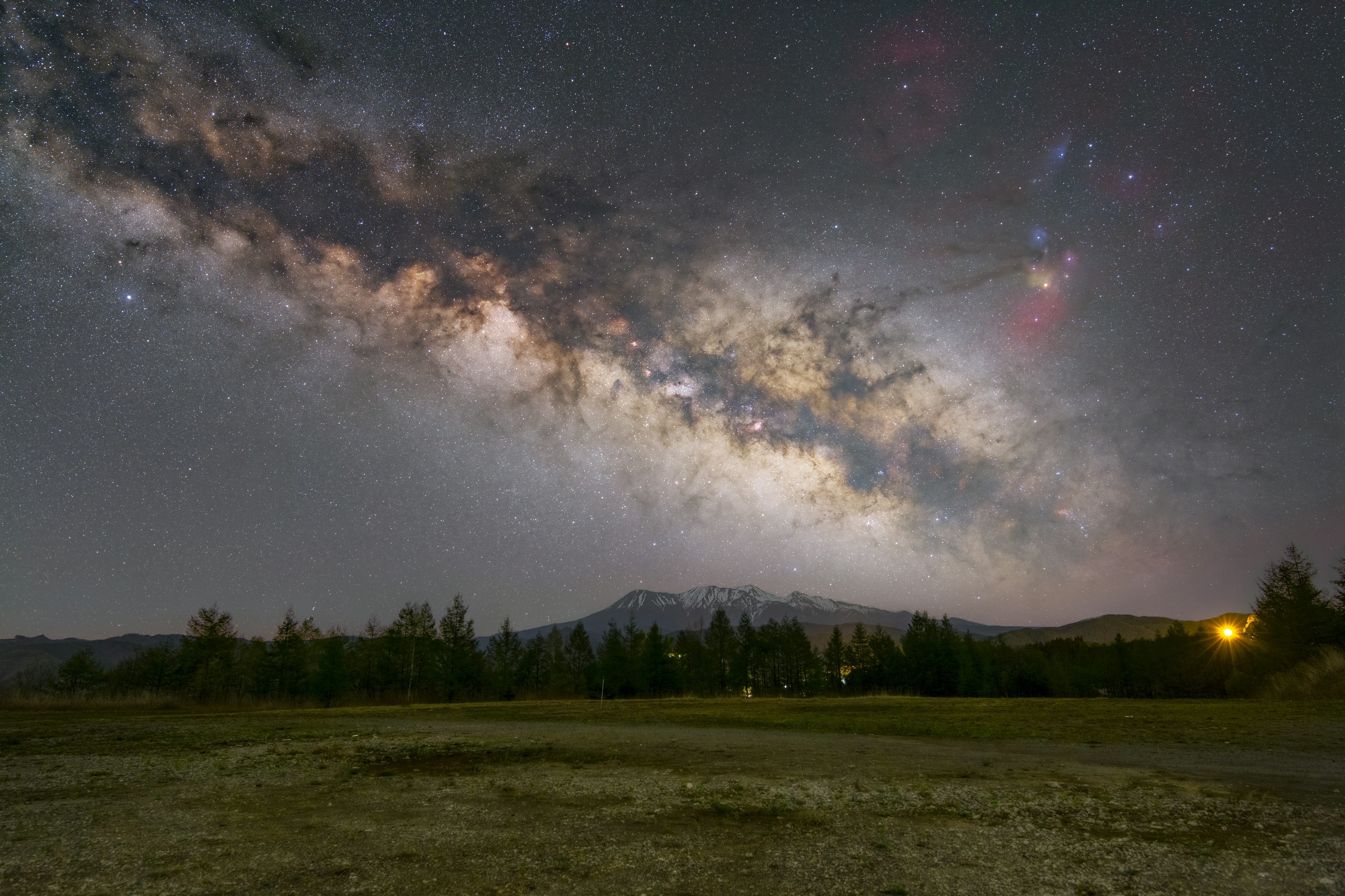 星空に広がる銀河系の美しい景色と山々のシルエット