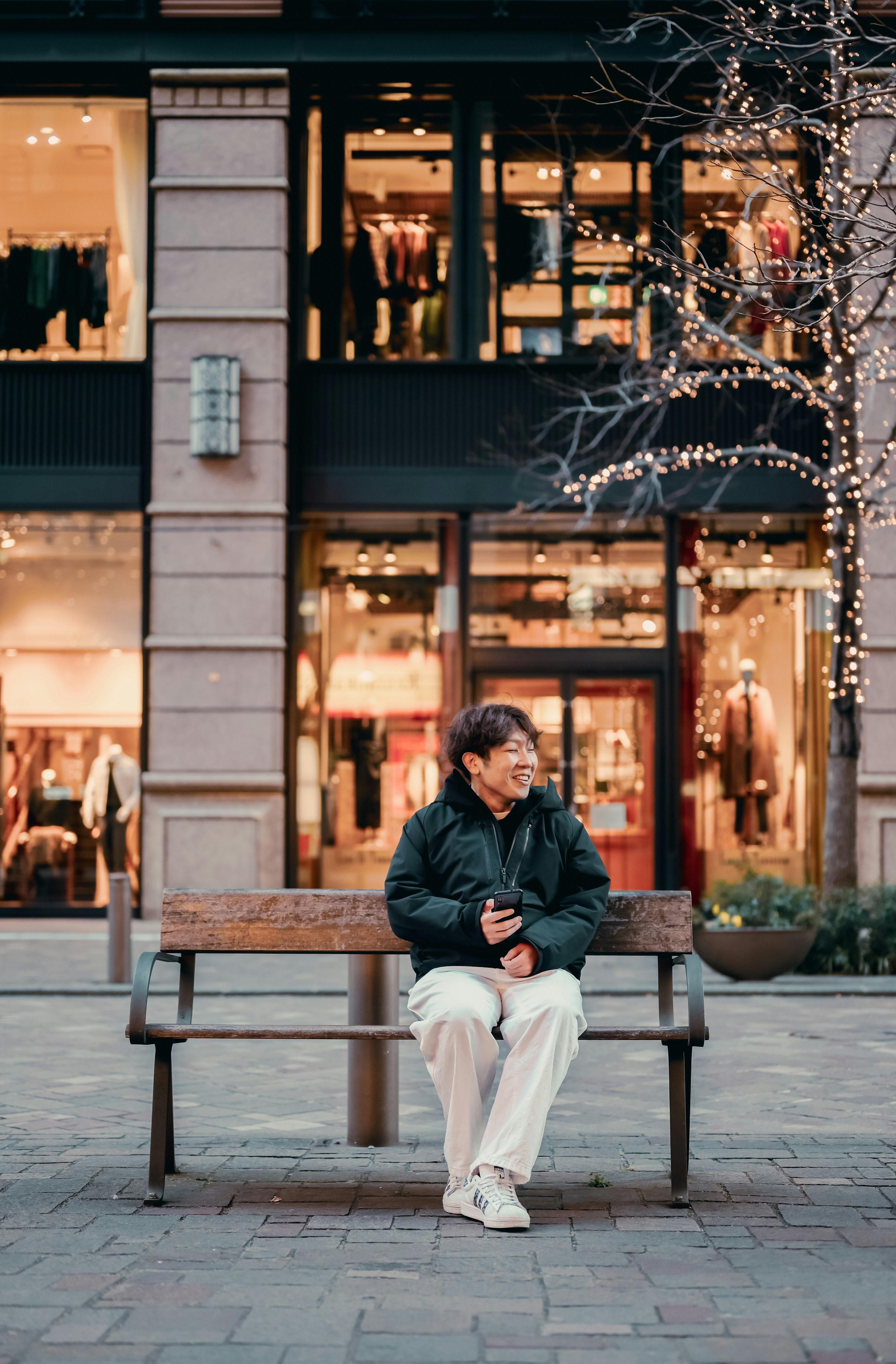 A man sitting on a bench in front of shops